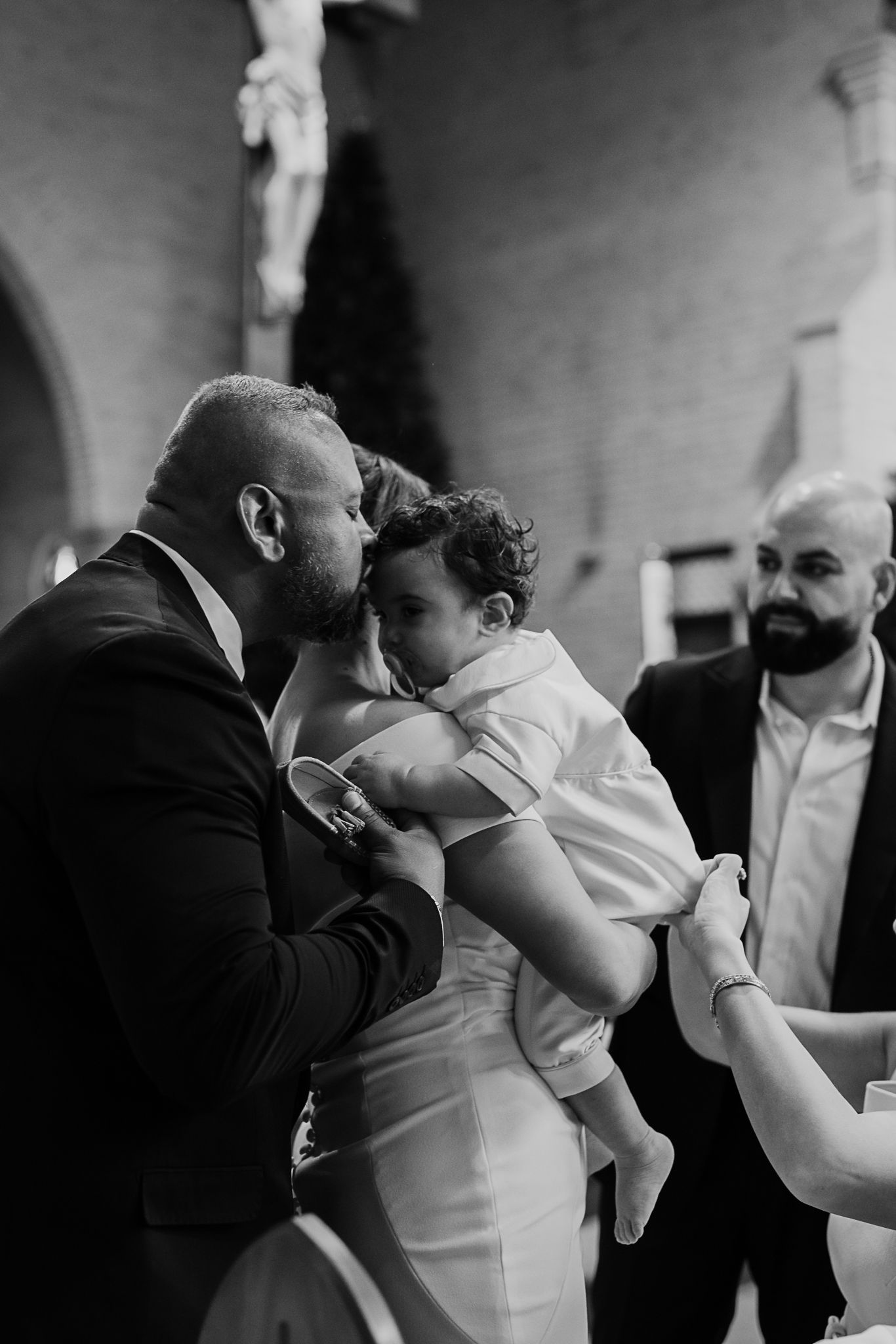 Emotional moment during baptism ceremony as adult holds small child in white clothing.