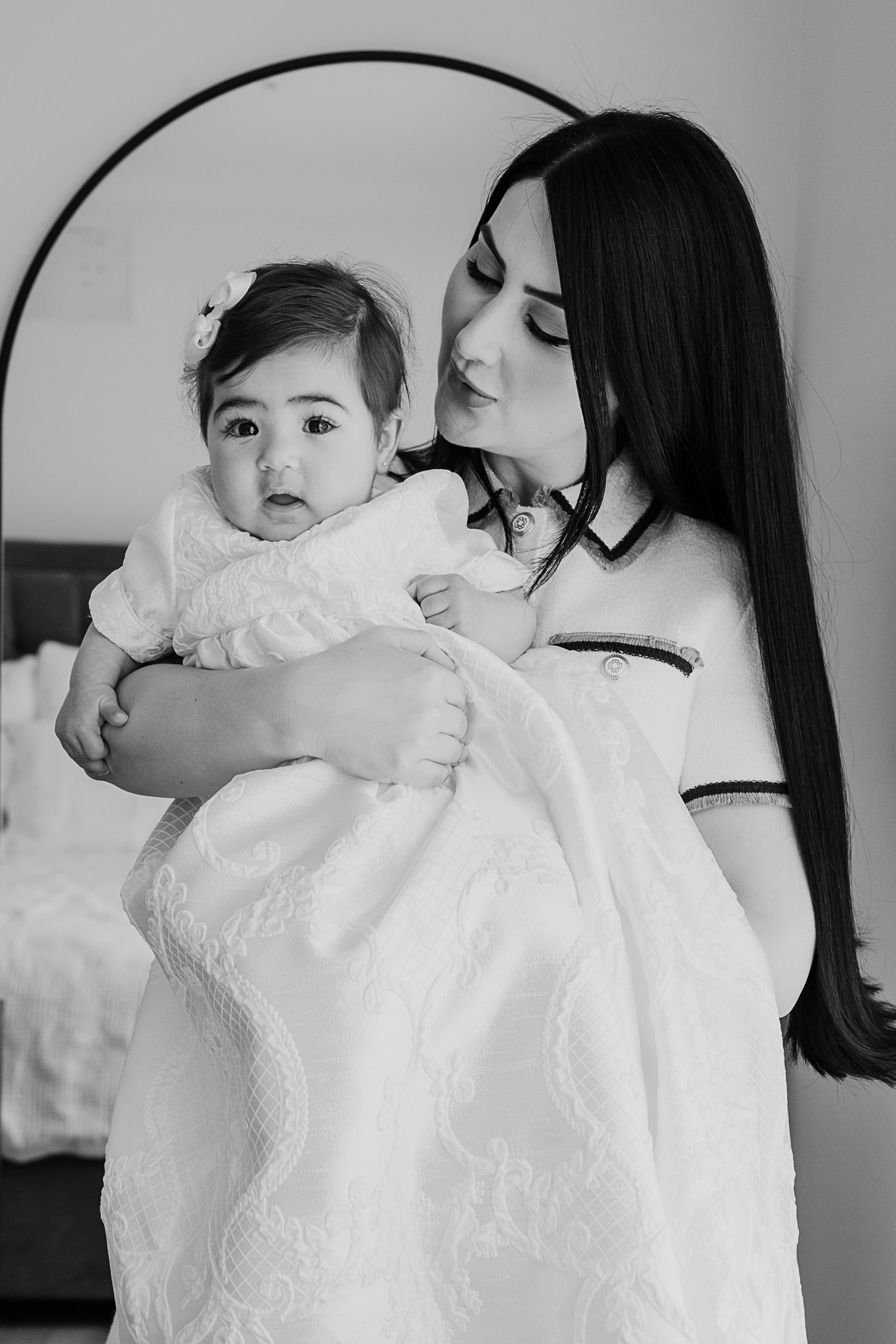 A classic black and white photo capturing a special christening moment with a baby in traditional white gown.