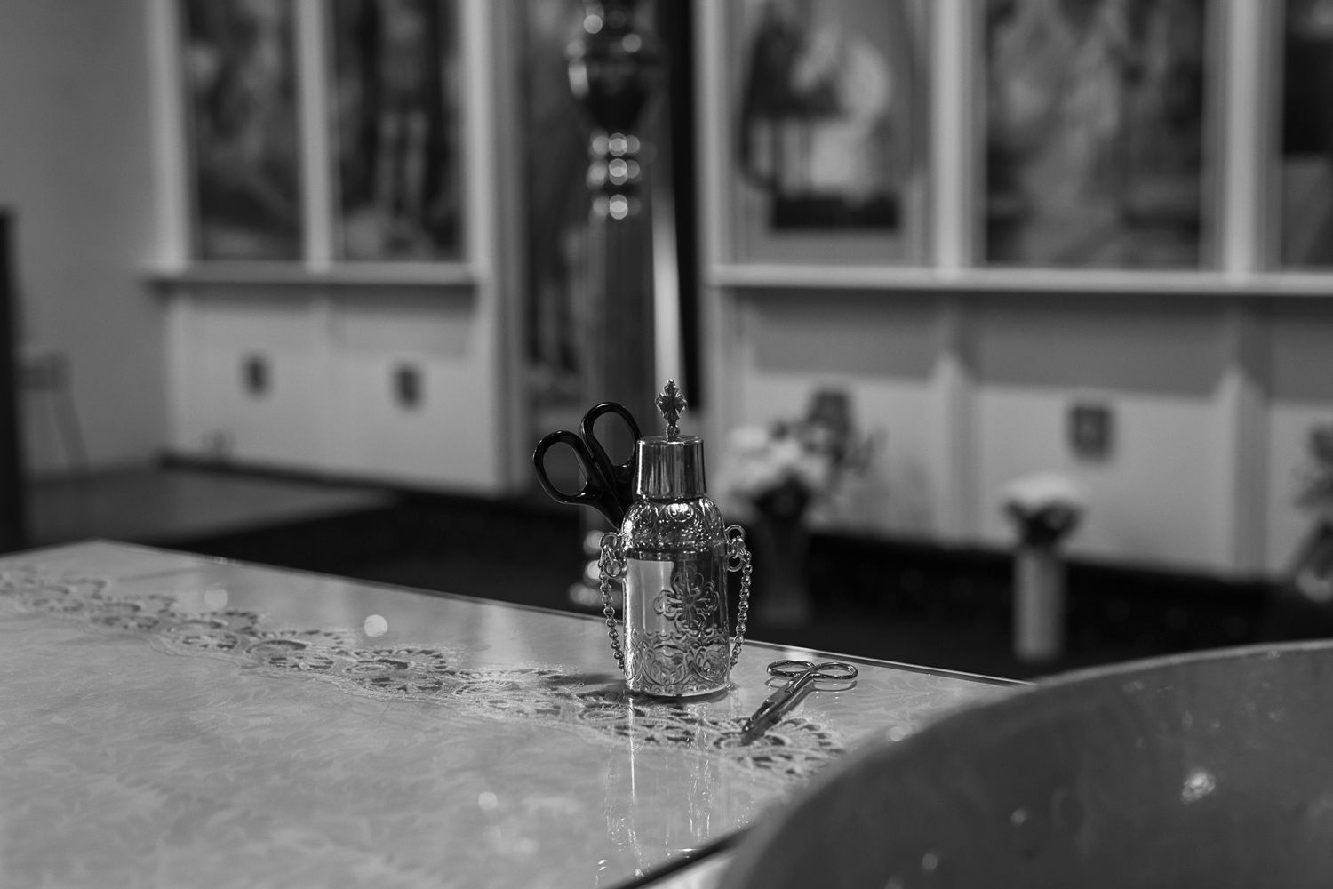 Black and white close-up of baptismal oils and holy water vessels on church altar.