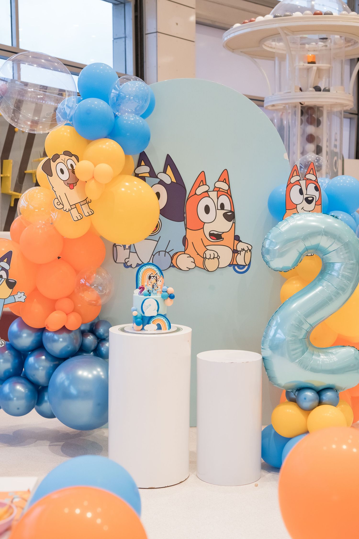 Bluey themed birthday party decoration with orange and blue balloon arrangements and number 2 balloon.