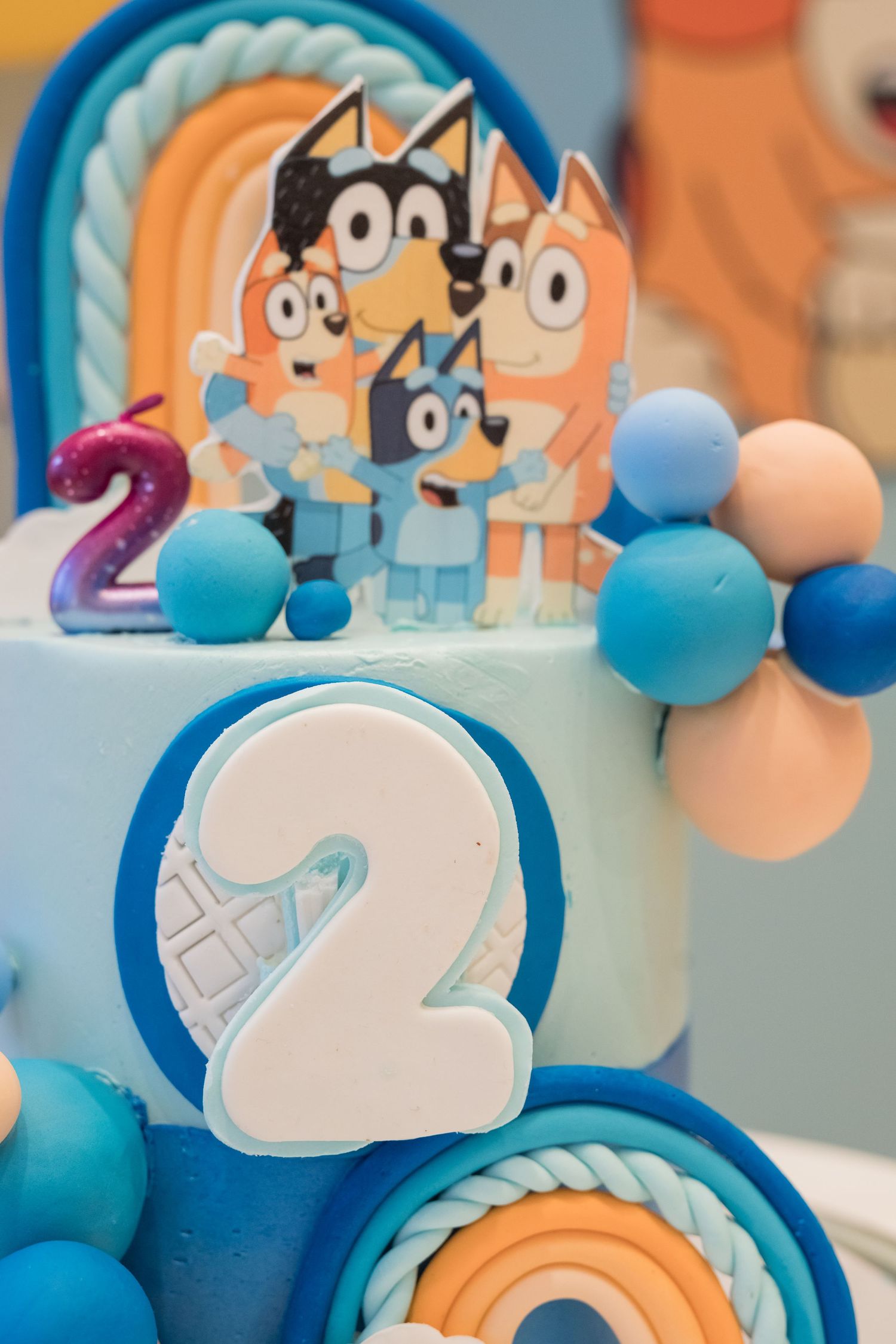 Close-up of a Bluey themed birthday cake with blue and orange balloon decorations.