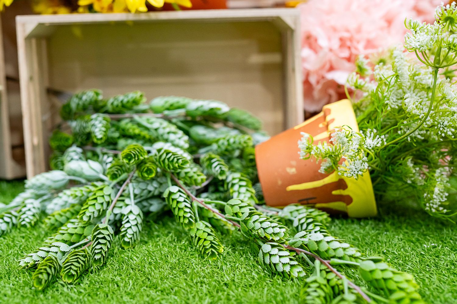 Close-up of faux pine branches arranged on artificial grass for party decor.