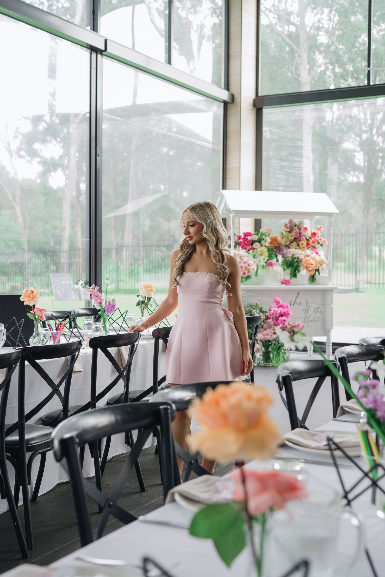 Light-filled venue features elegant black crossback chairs and colorful floral arrangements in a bright sunroom setting.