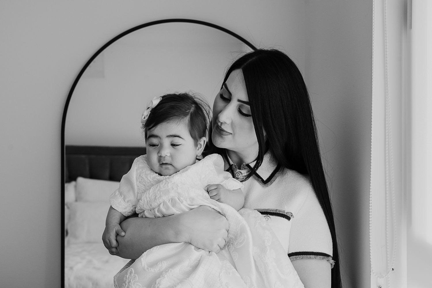 An intimate black and white portrait of a tender moment during a baptism ceremony.