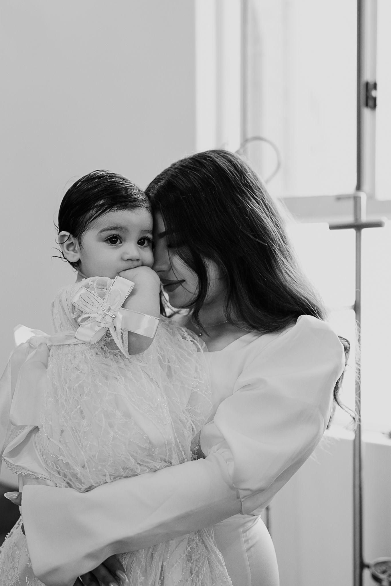 A tender moment between parent and child in white baptismal attire.