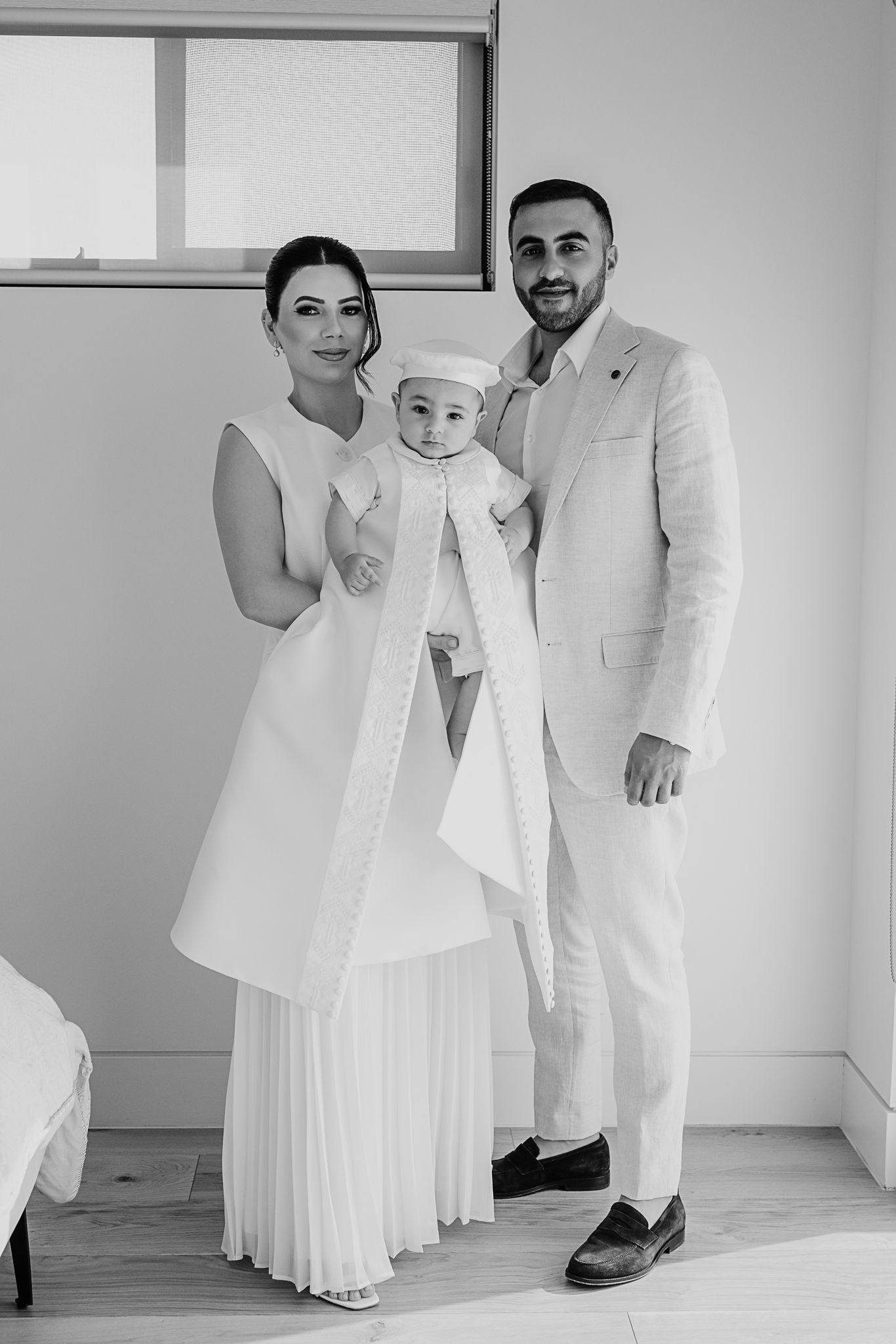 Black and white portrait of a family dressed in white formal attire.
