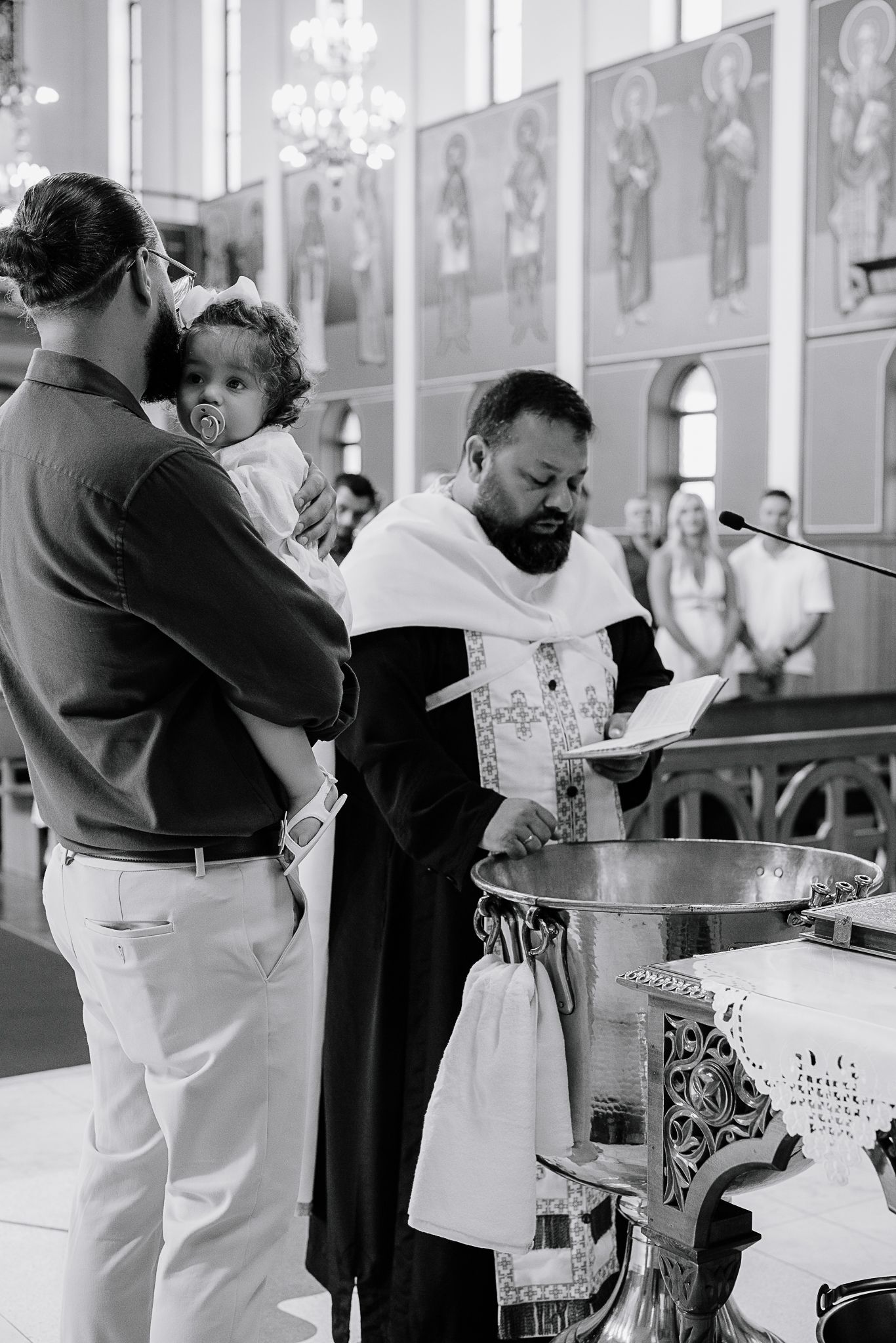 Baptism ceremony in progress with priest performing the ritual at church altar.