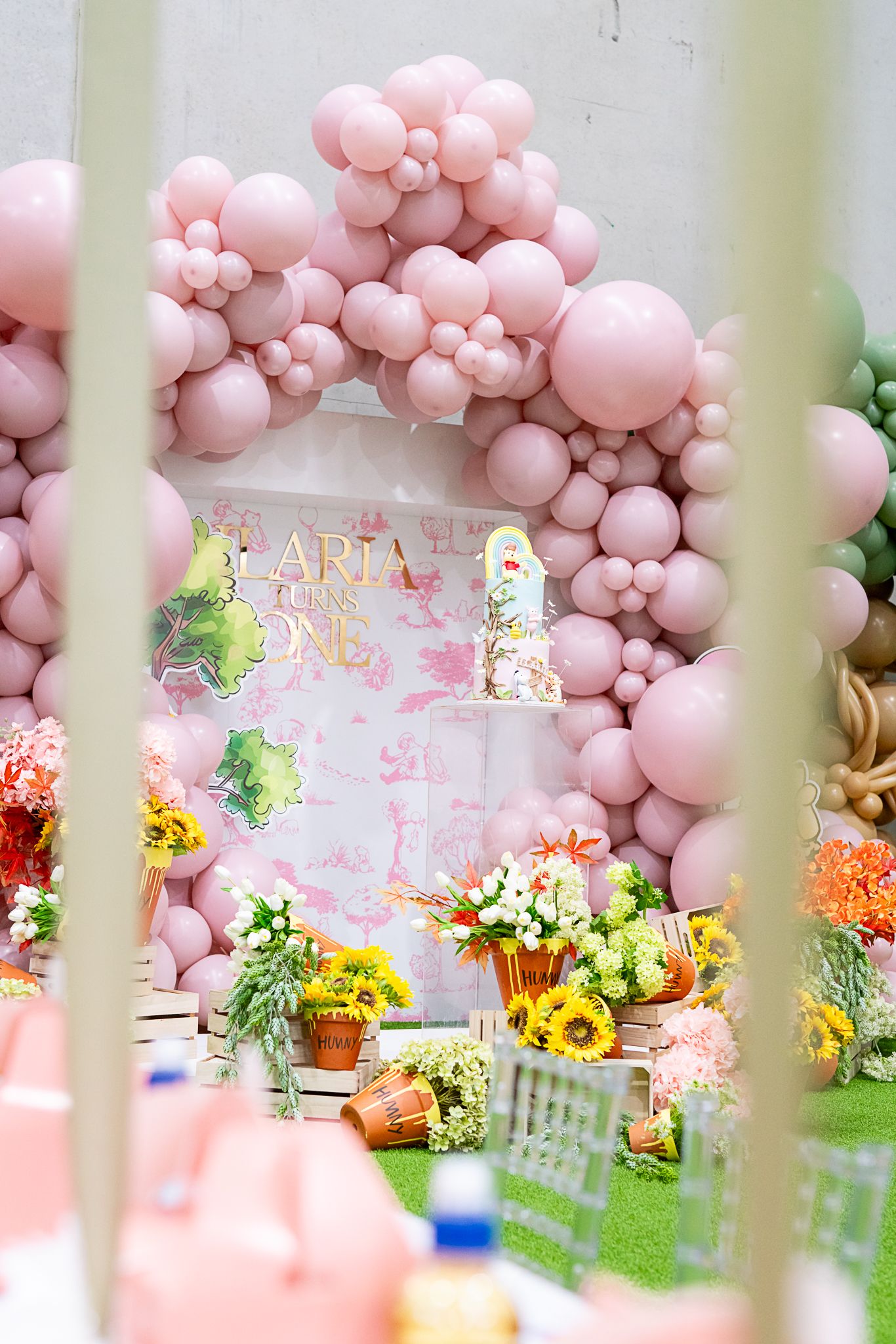 Pink balloon arch with floral arrangements and sunflowers creating an enchanting party atmosphere.