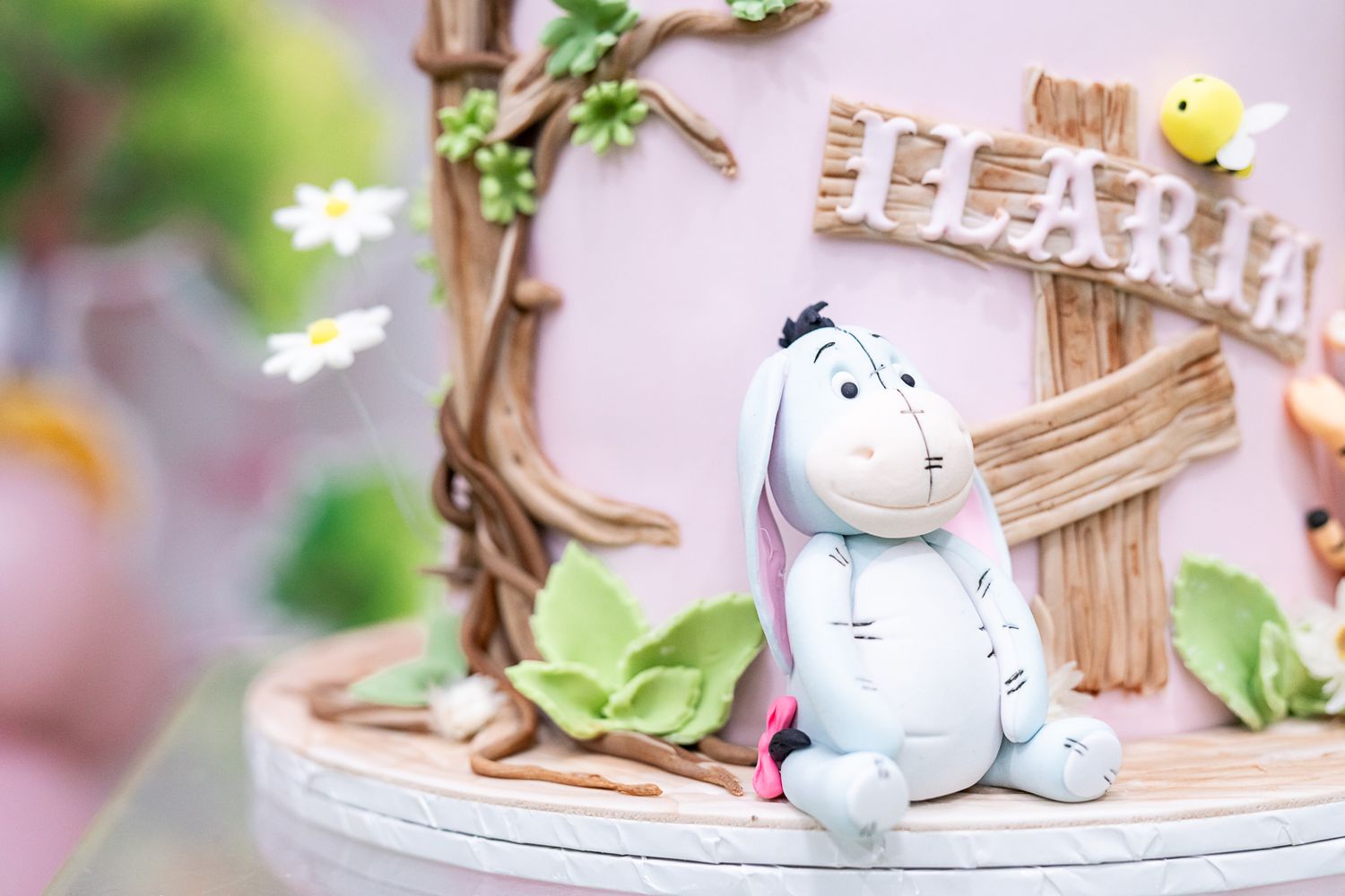 Decorative cake topper featuring a cute cartoon donkey figure next to a wooden fence.