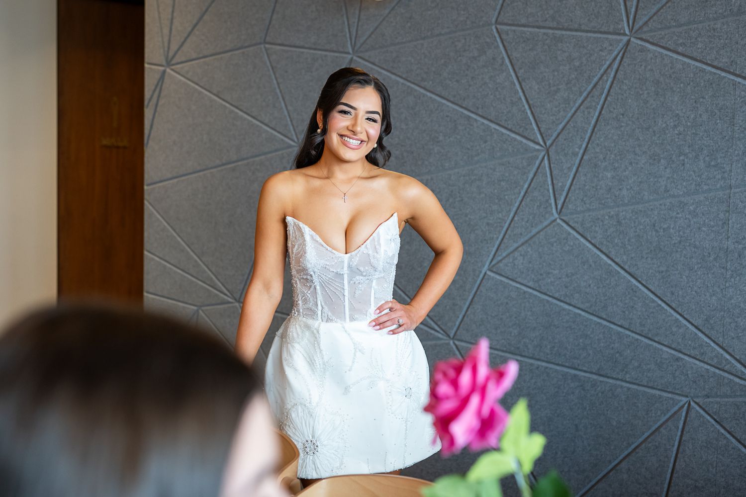 White bridal dress displayed against geometric patterned wall with floral decor.