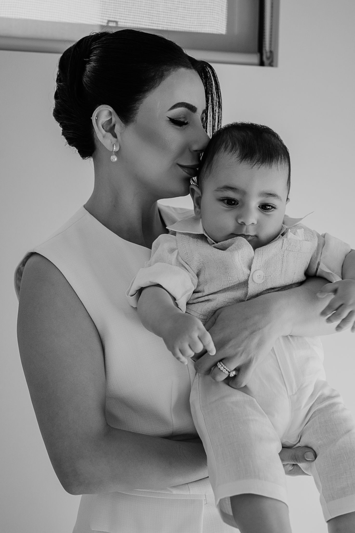 Intimate black and white portrait of woman in white dress holding an infant.