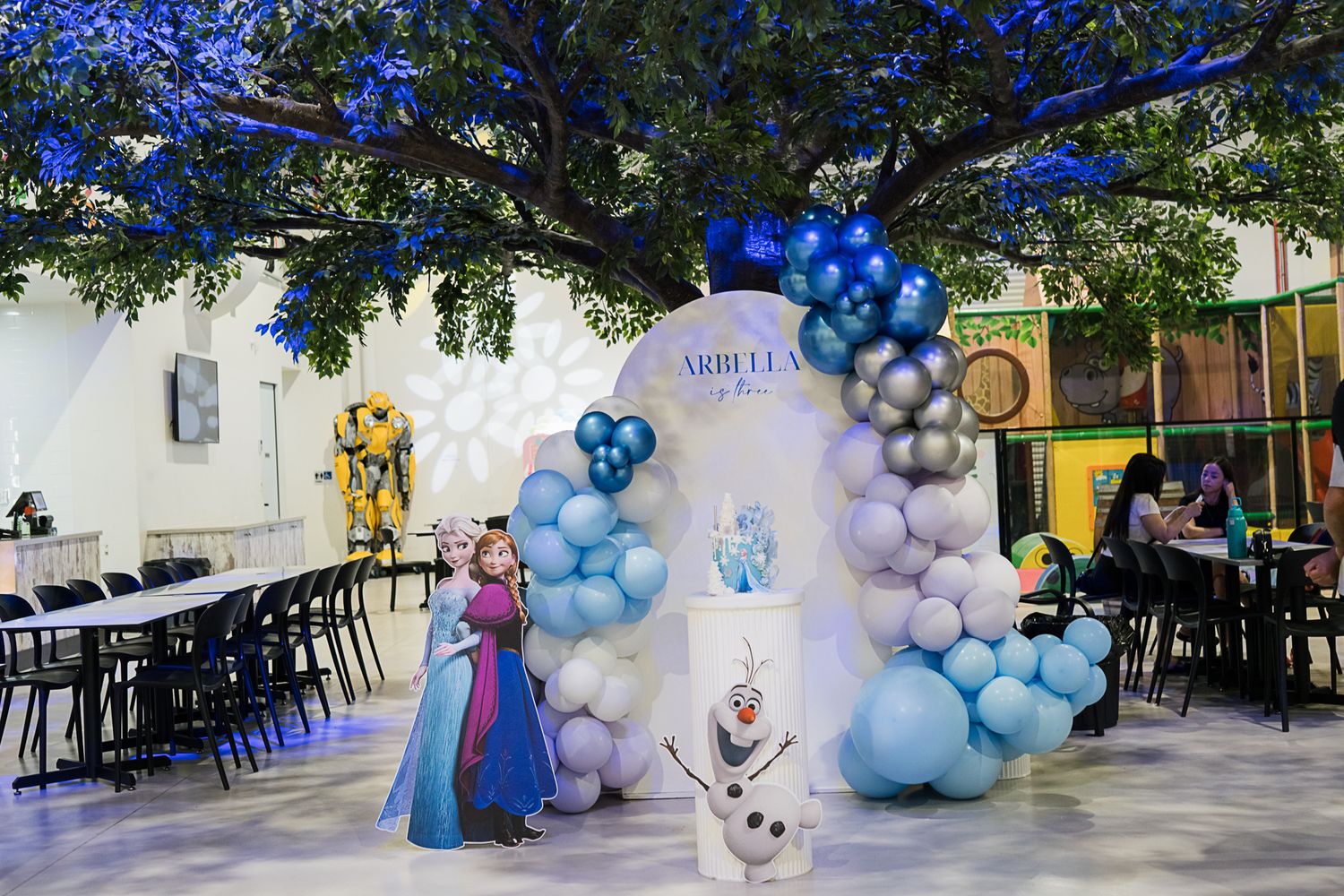 Winter party setup with blue balloon arch, decorative backdrop, and themed party decor.