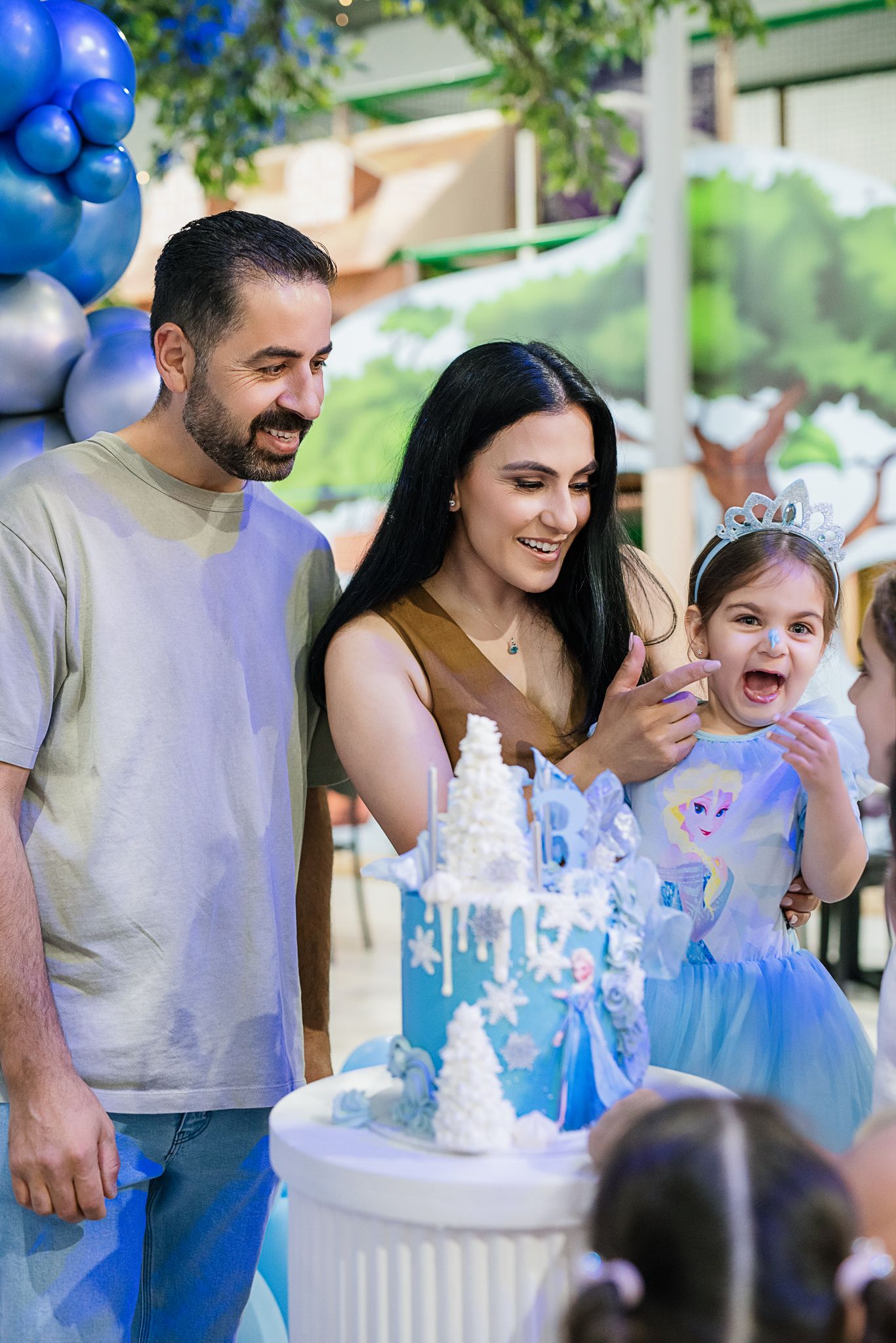 Birthday celebration with a winter-themed cake and blue balloon decorations.