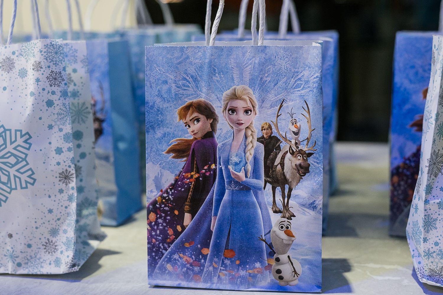 Frozen themed party favor bags with snowflake decorations displayed in a row.