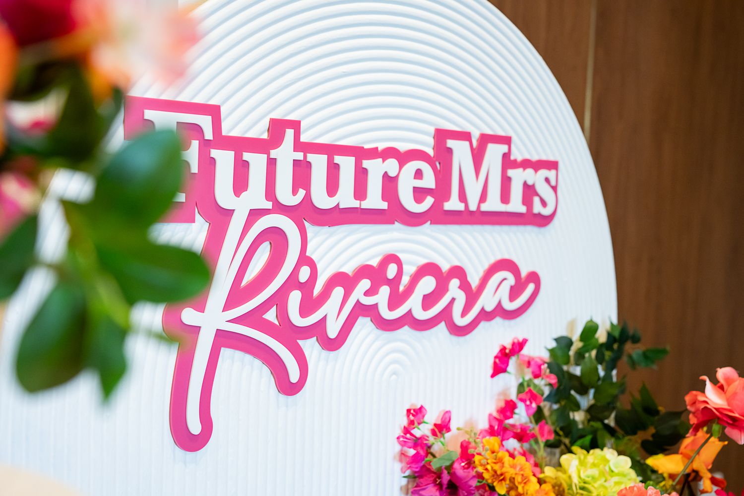 Pink 'Future Mrs' text display against white curved backdrop with floral decorations.