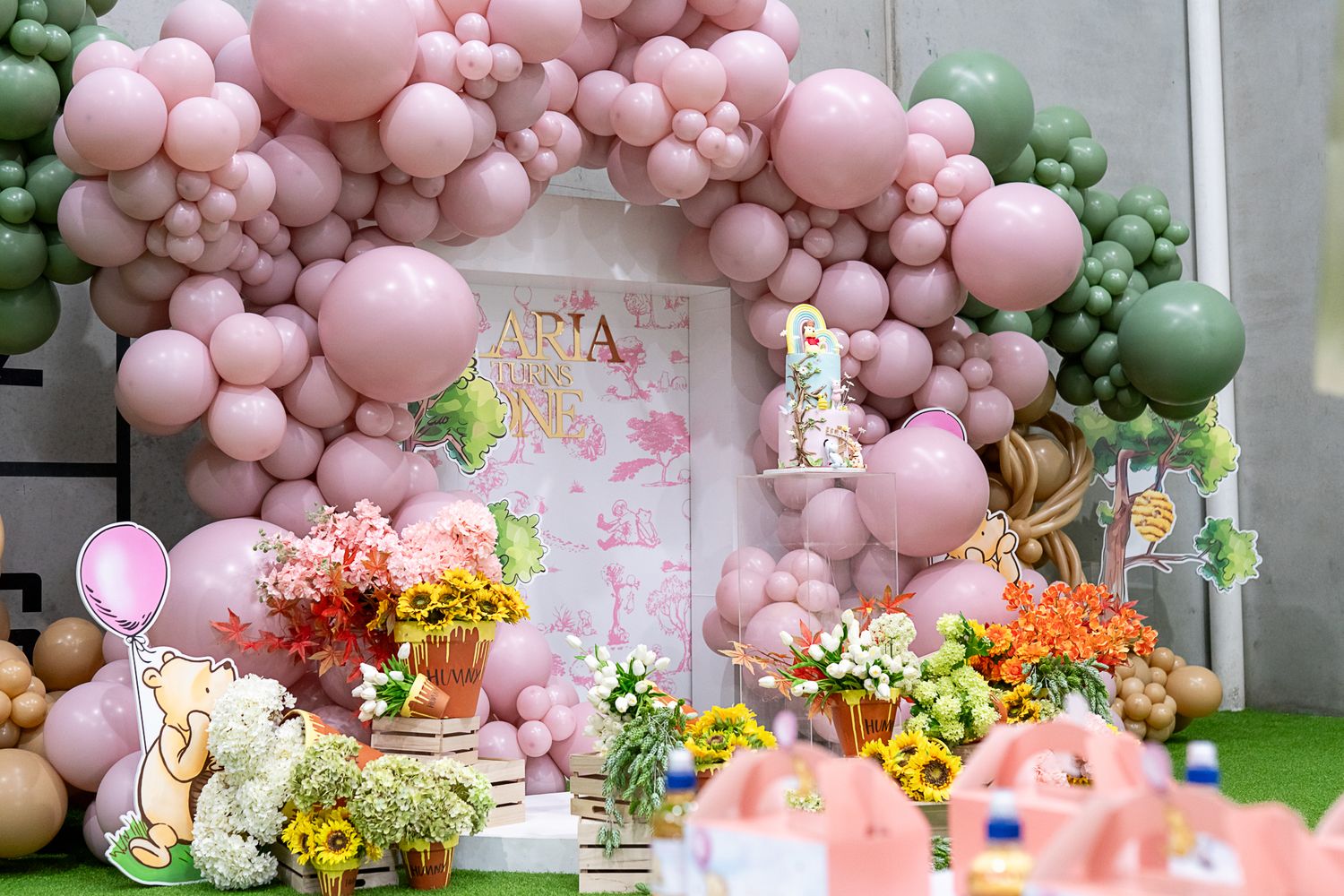 Stunning balloon garland in pink and green with colorful floral arrangements and party decorations.