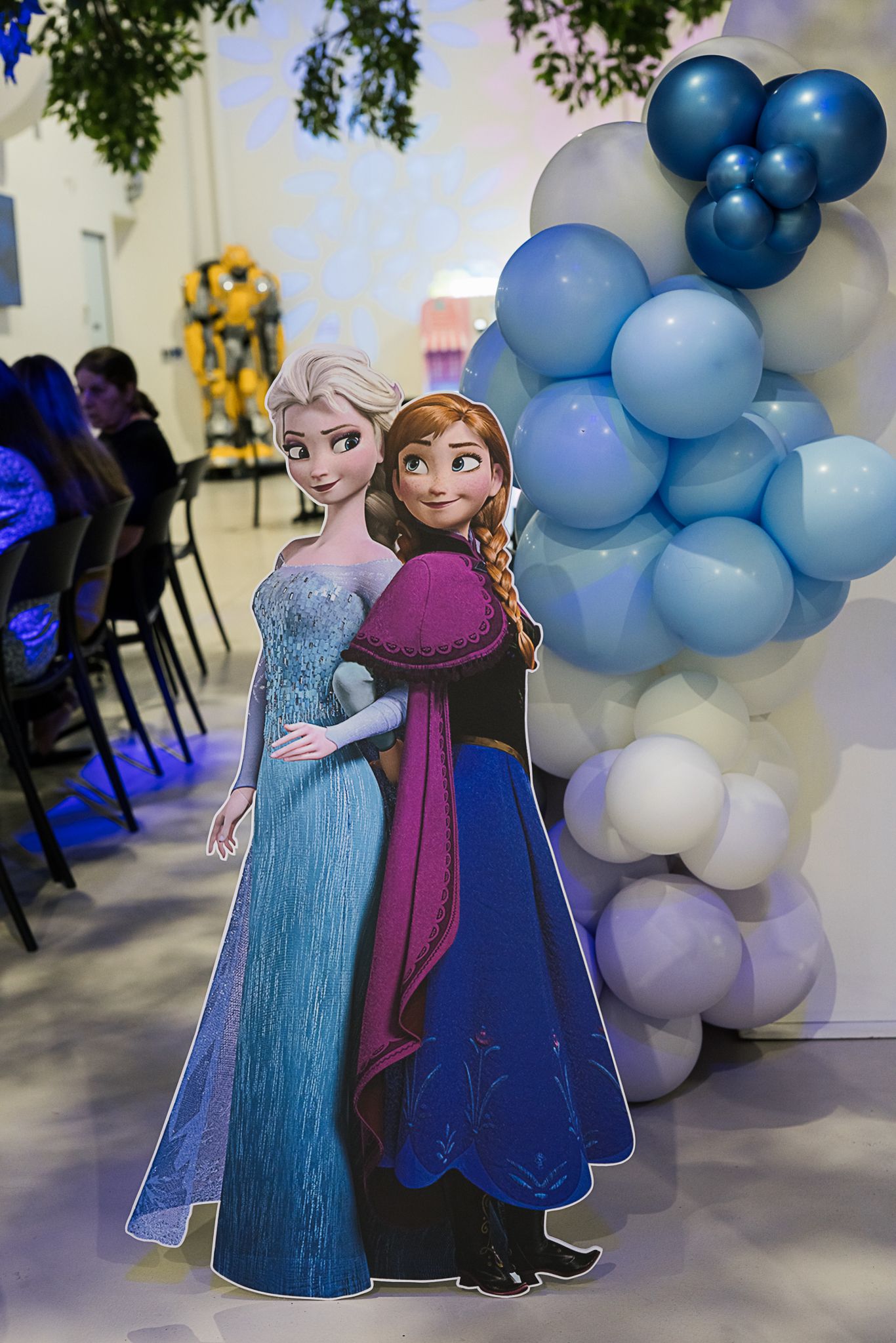 Frozen cardboard standee of Elsa and Anna with blue ombre balloon arch decoration.