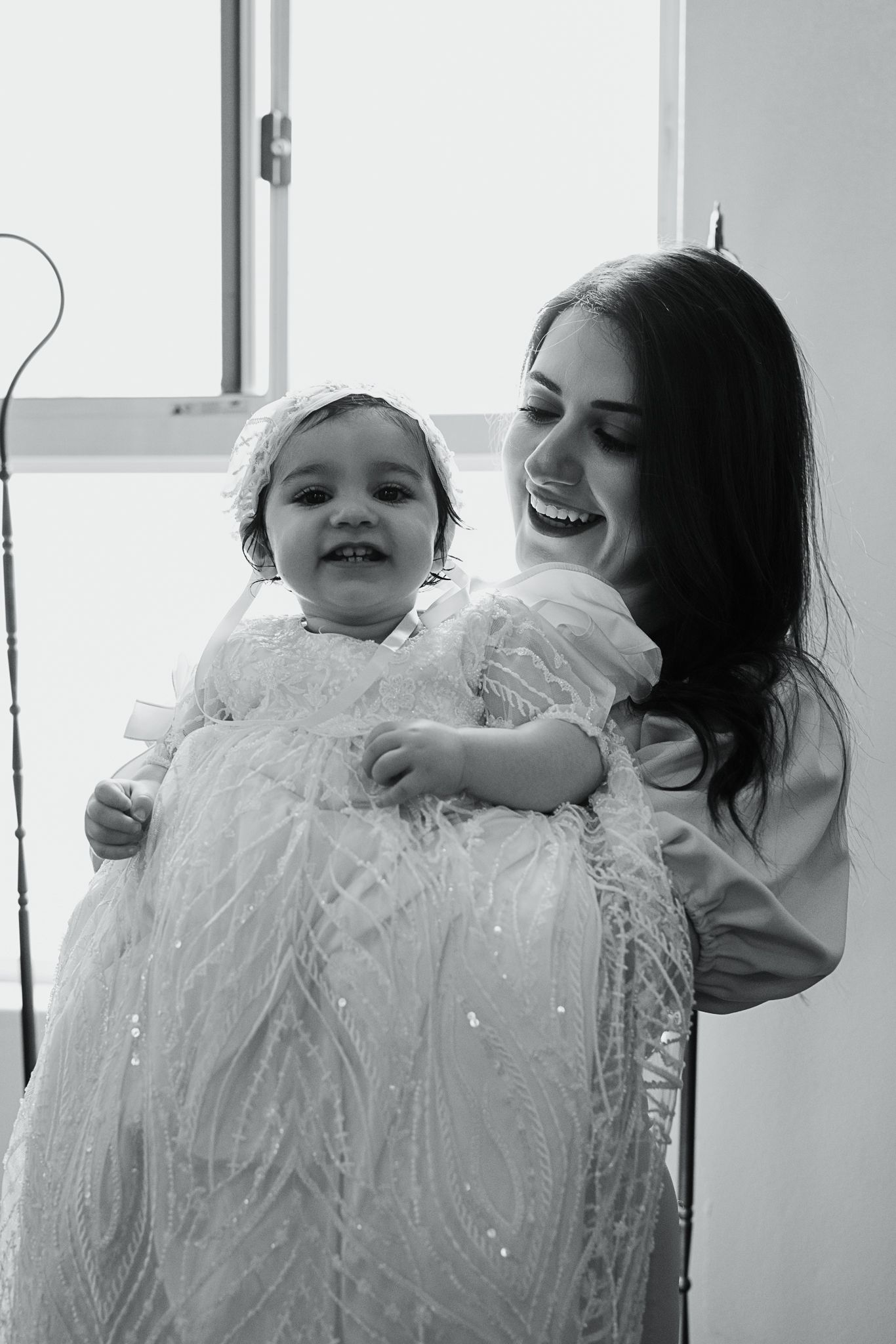 Joyful moment during baptism ceremony with white christening gown.