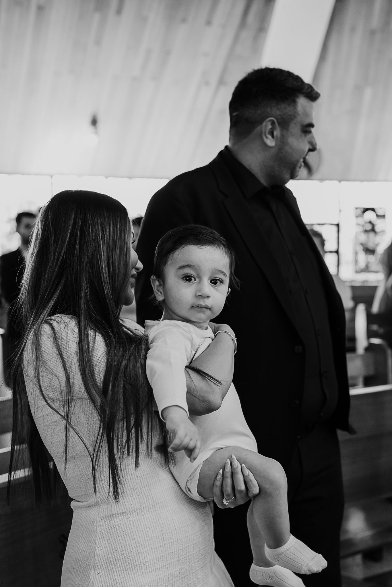 Black and white candid photo of family during religious ceremony.