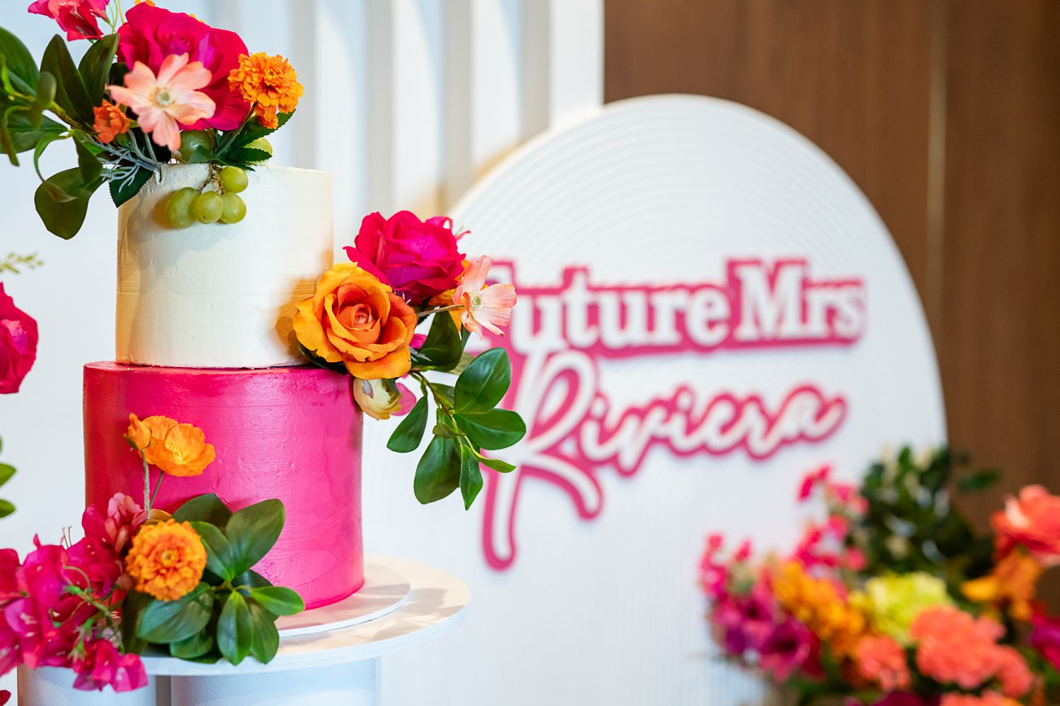 Close-up of white arch display with pink lettering and colorful floral decorations.