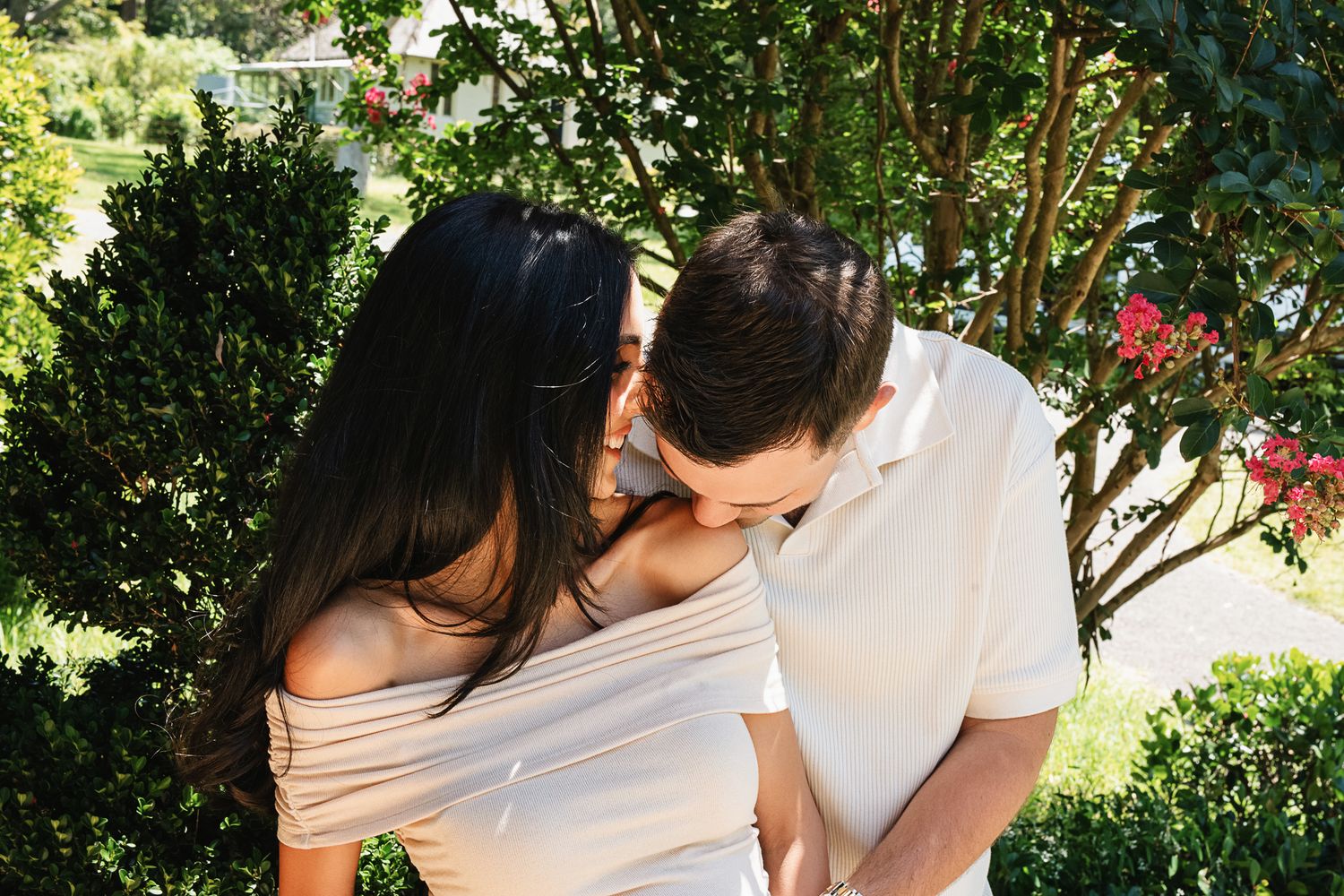 A couple shares an intimate moment together during their maternity photoshoot in a garden setting.