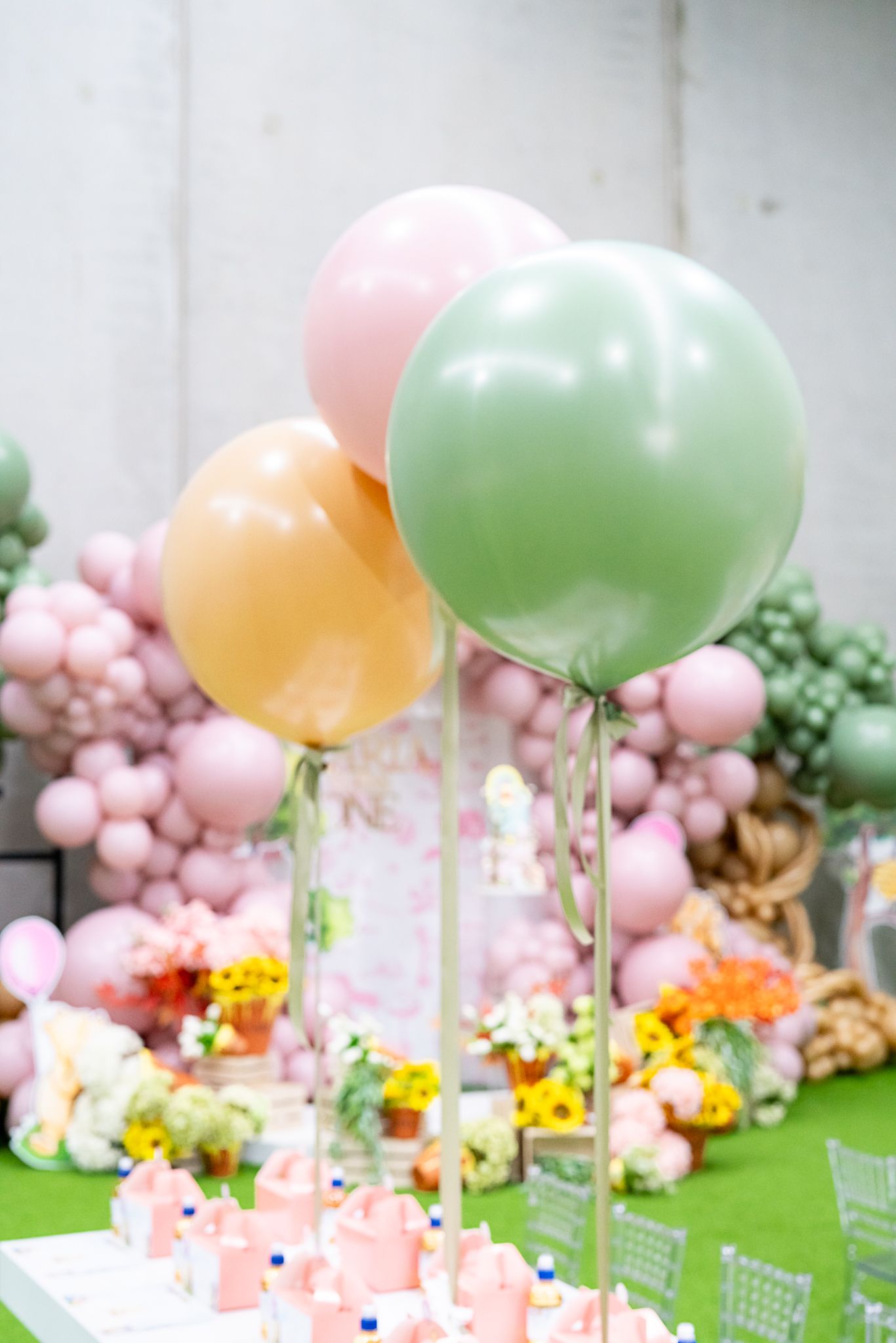 Pastel balloon centerpieces in pink, green, and yellow colors floating above party tables.