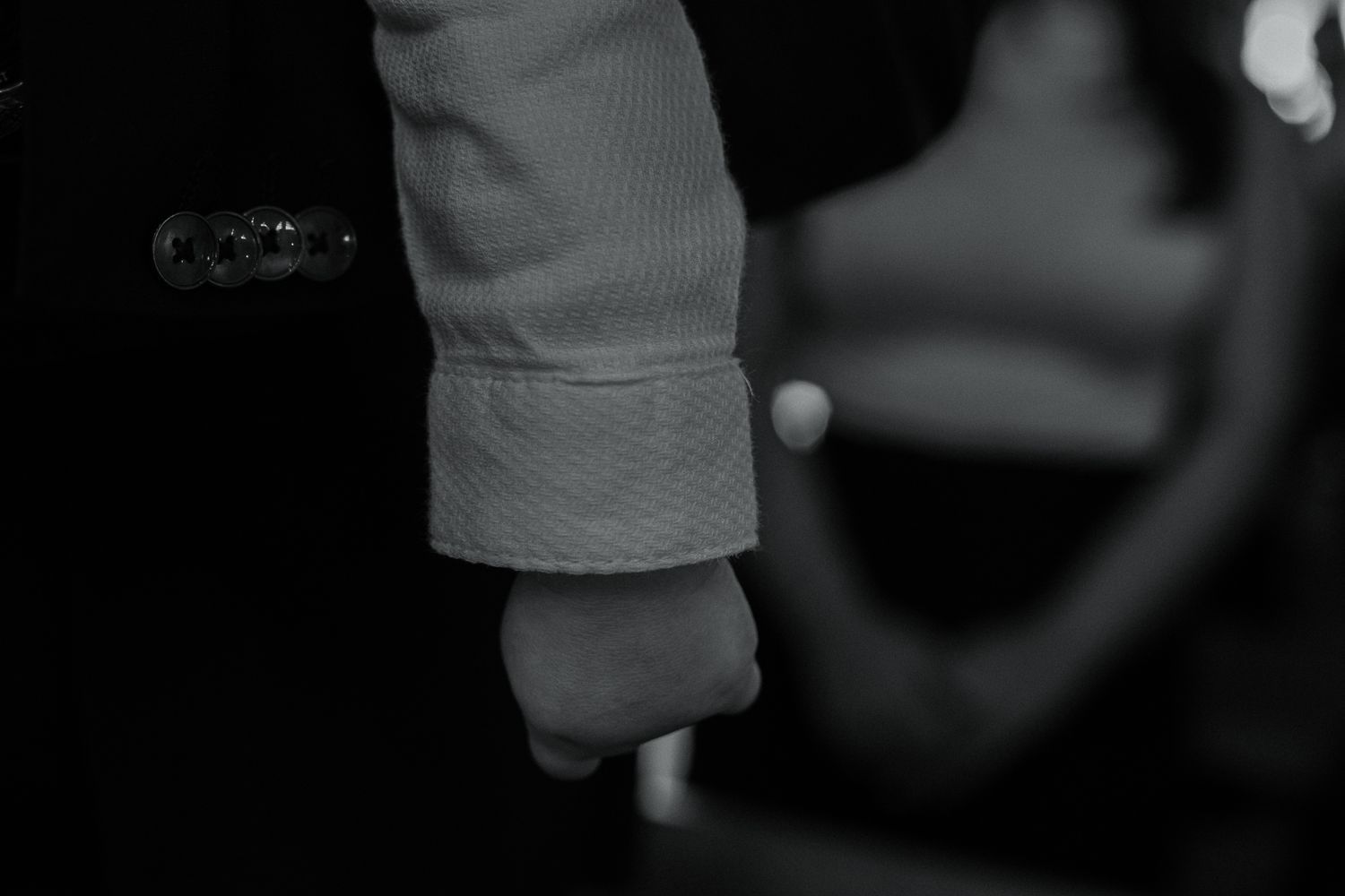 Close-up black and white image of a person's sleeve cuff in soft focus.