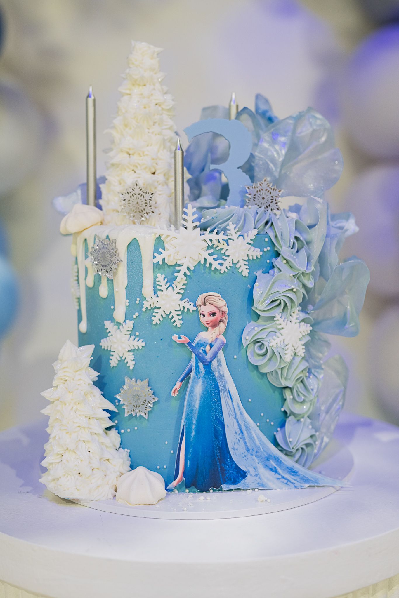 Winter-themed cake featuring blue icing, white snowflakes, and silver decorative elements.