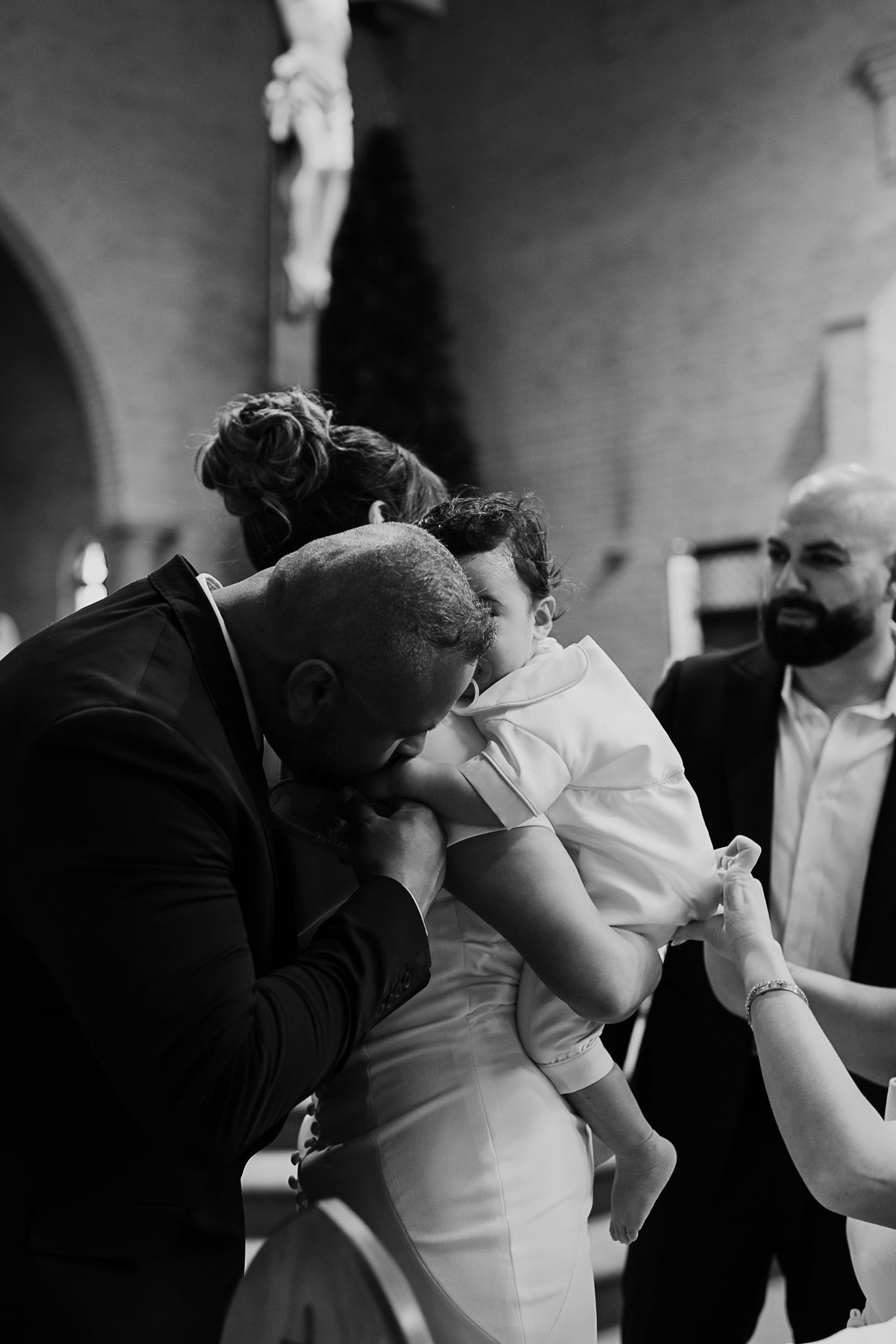 A tender moment captured in black and white at a wedding reception as people share an emotional embrace.