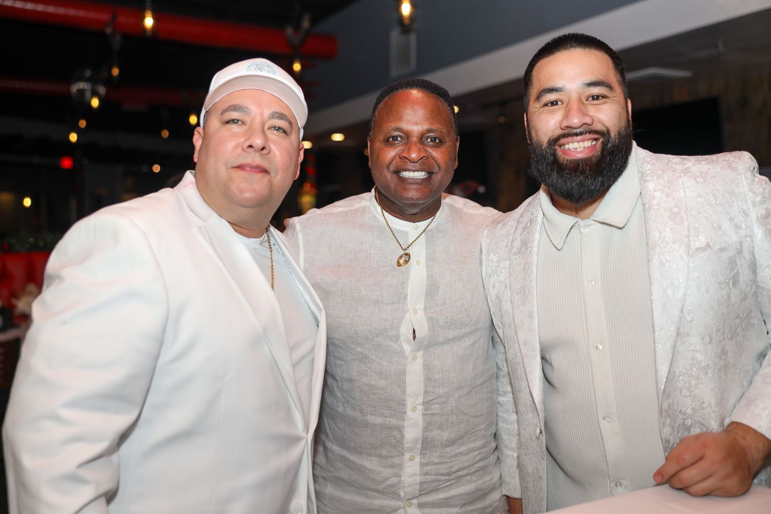 A group of people wearing white clothing pose together at what appears to be a social event or gathering.