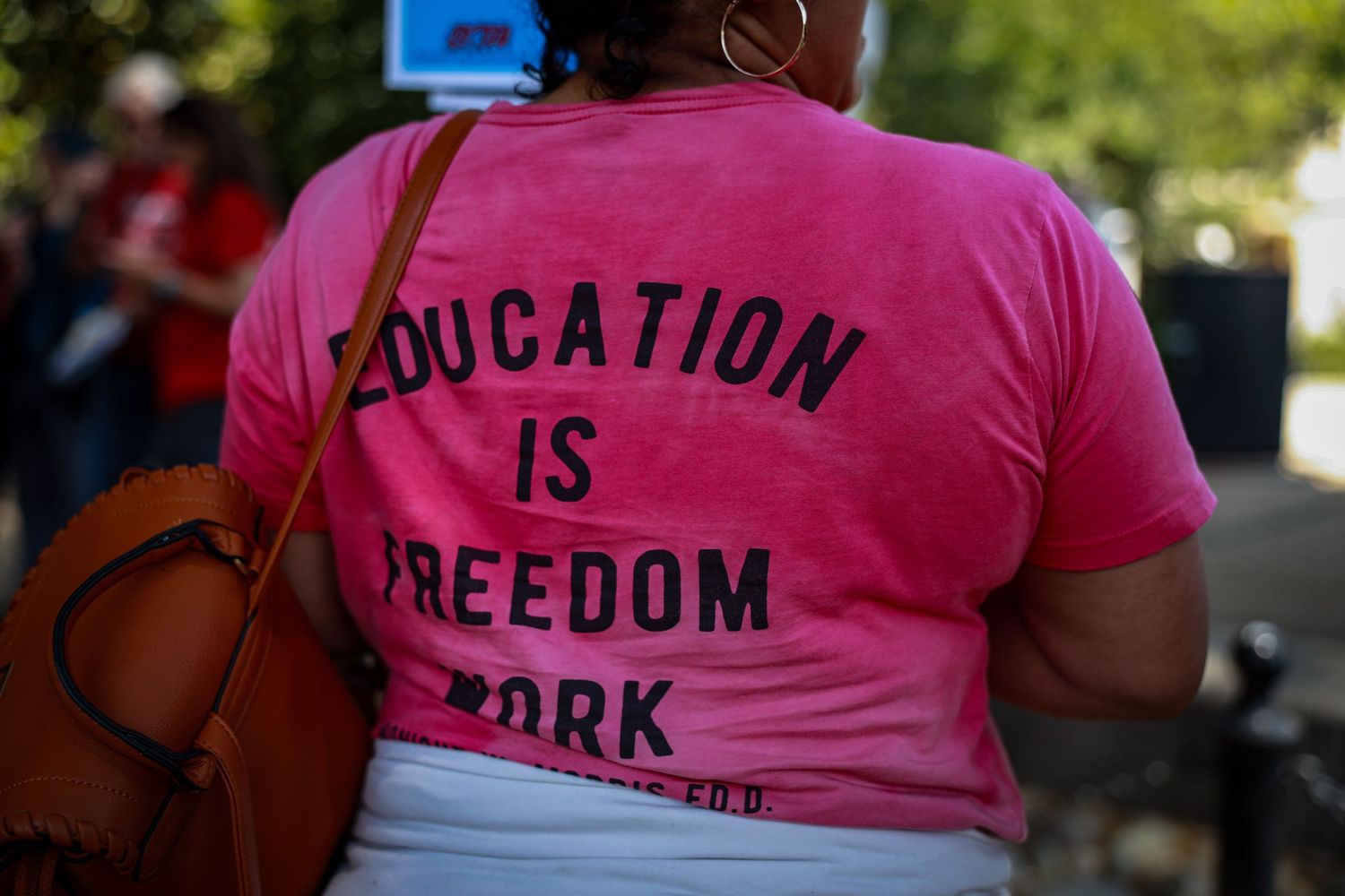 Someone wearing a bright pink t-shirt with text reading 'Education is Freedom' on the back.