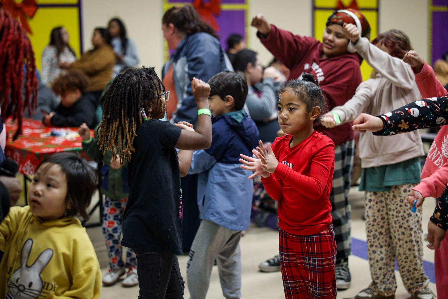 Children dance together in a colorful classroom during an indoor activity session.