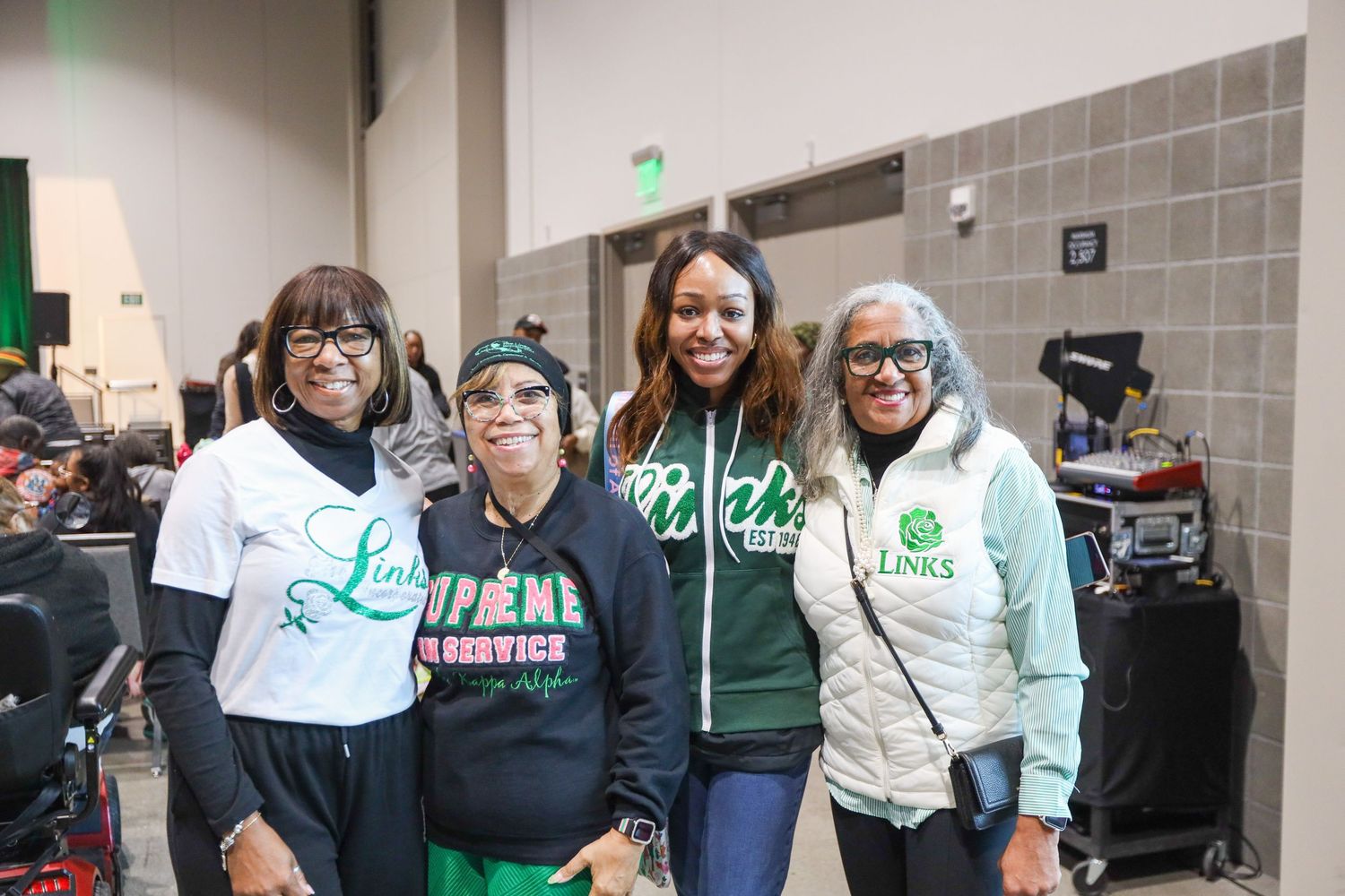 Group of people wearing green and white clothing pose together at what appears to be a school or community event.