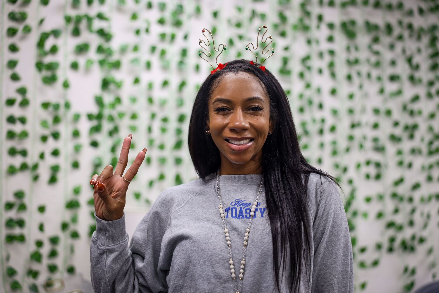 Three photos of someone wearing a gray sweatshirt posing against a wall with green vine decorations.