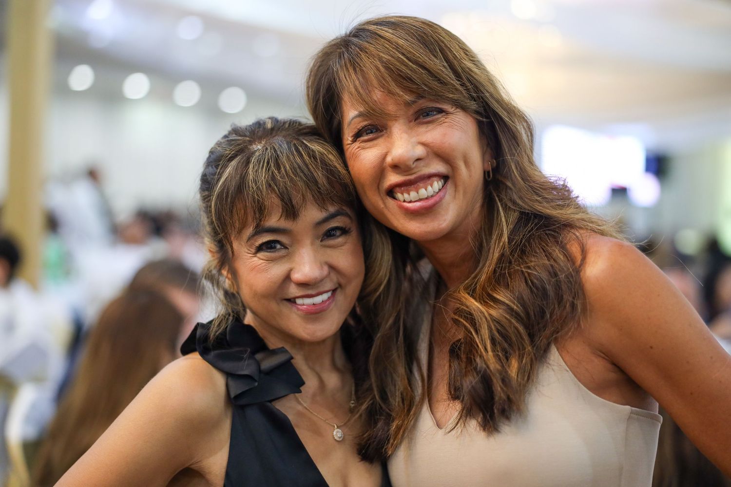 A group of friends smile and laugh together while posing at what appears to be a social gathering.