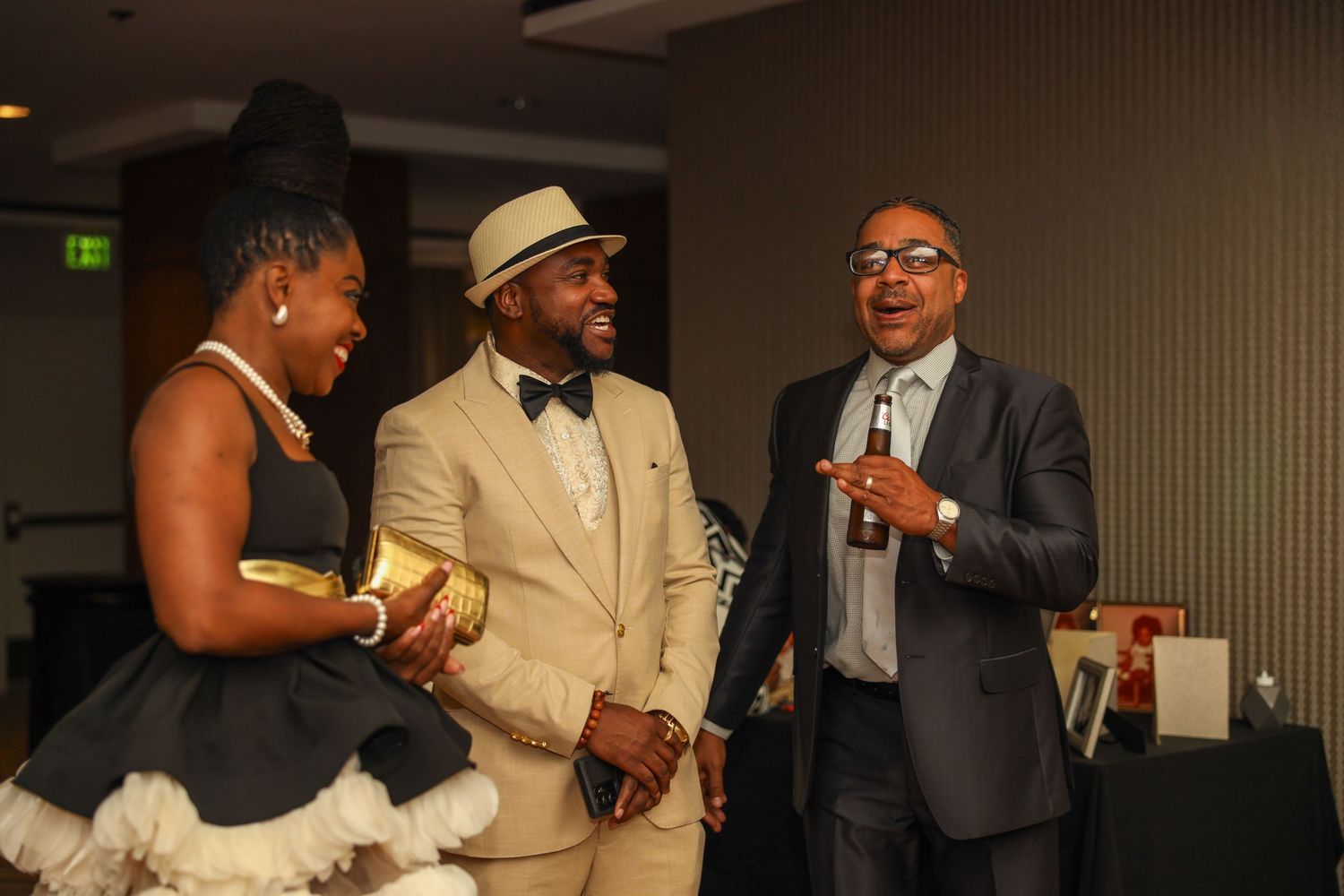 Guests in formal attire including suits and bow ties gather at an elegant indoor event.