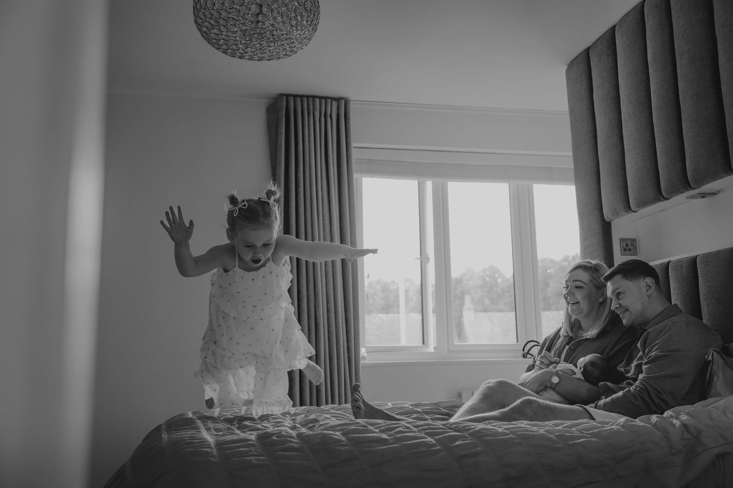 Silhouetted figures relaxing in a modern room with large windows and curtains.