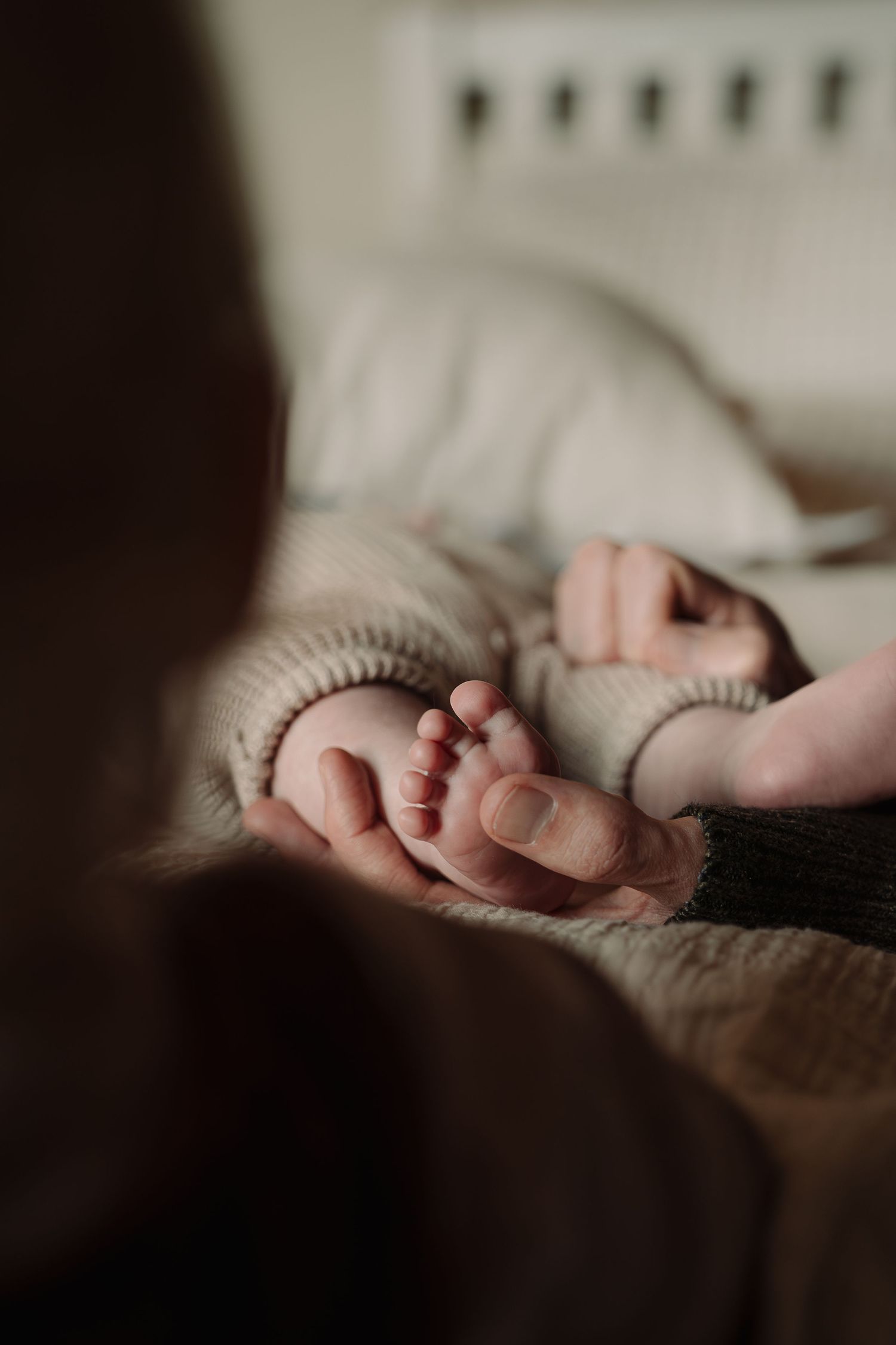 Delicate baby feet in soft knit clothing captured in gentle natural light.