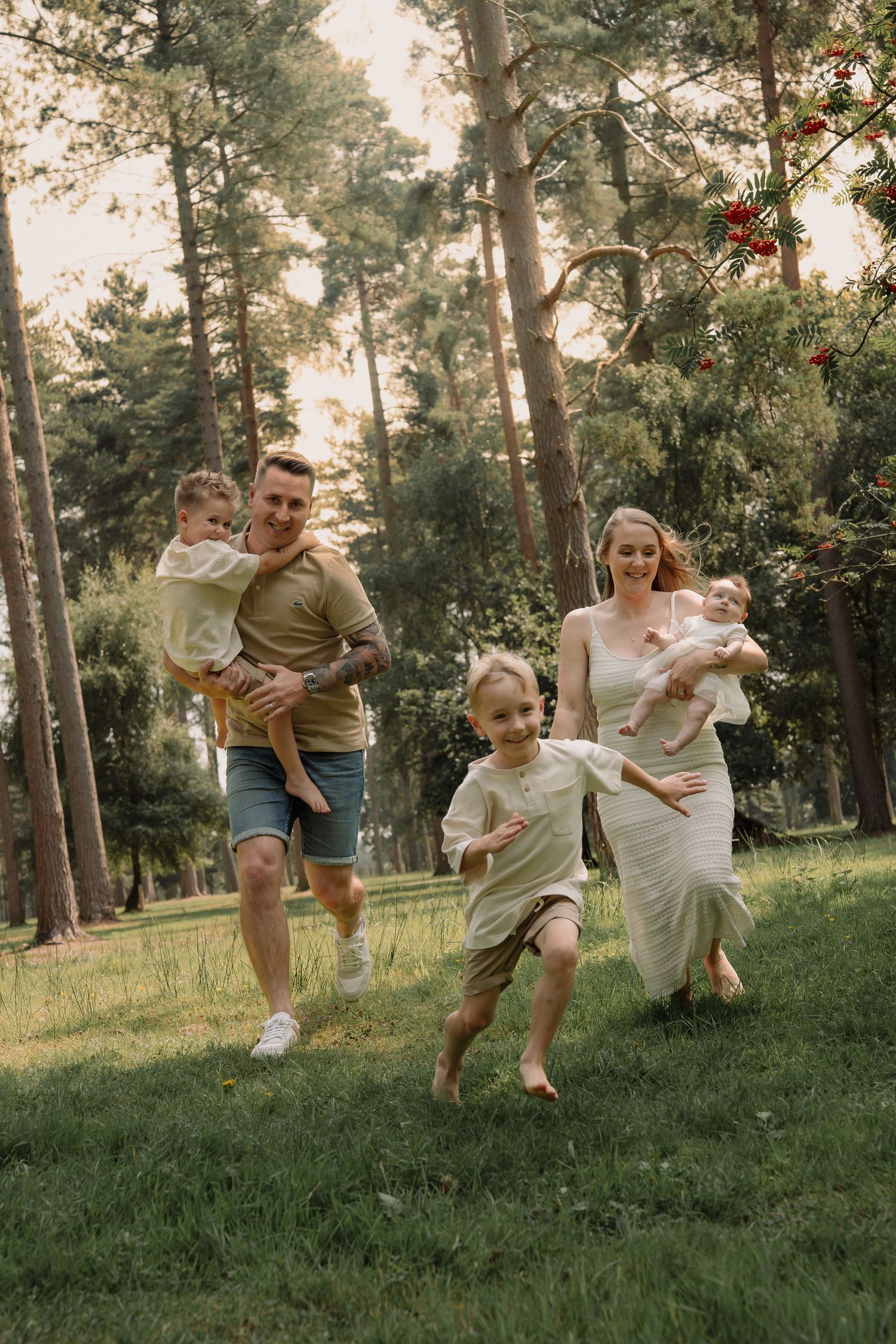 A group enjoys a playful moment together in a sunlit forest setting with pine trees and grassy ground.
