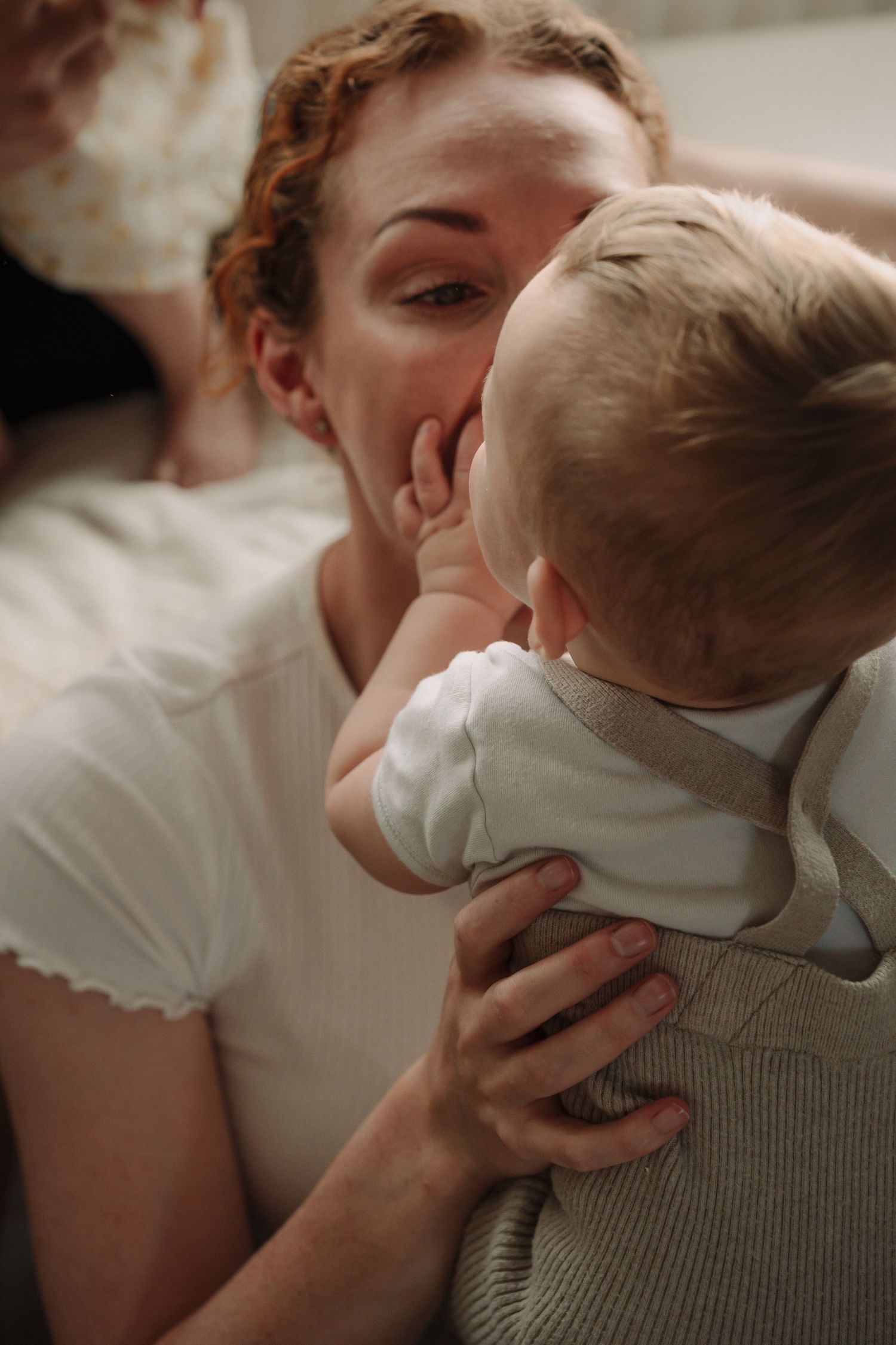 A tender moment between parent and baby in soft lighting showing gentle affection and care.