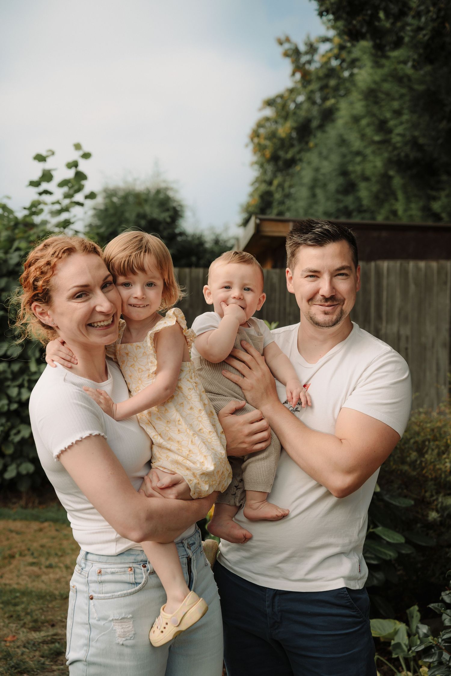 A family shares joyful moments together in a backyard photo series with natural lighting and greenery.