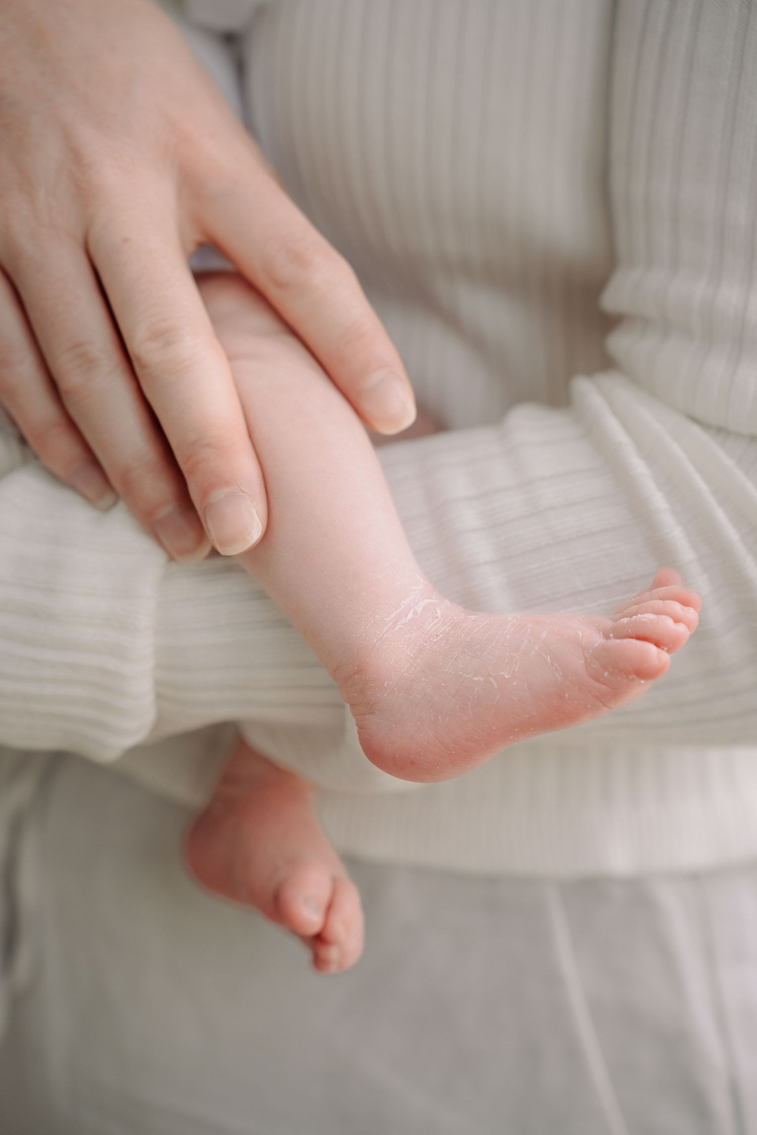 A series of close-up shots showing a baby's tiny foot being gently held and examined against a white background.