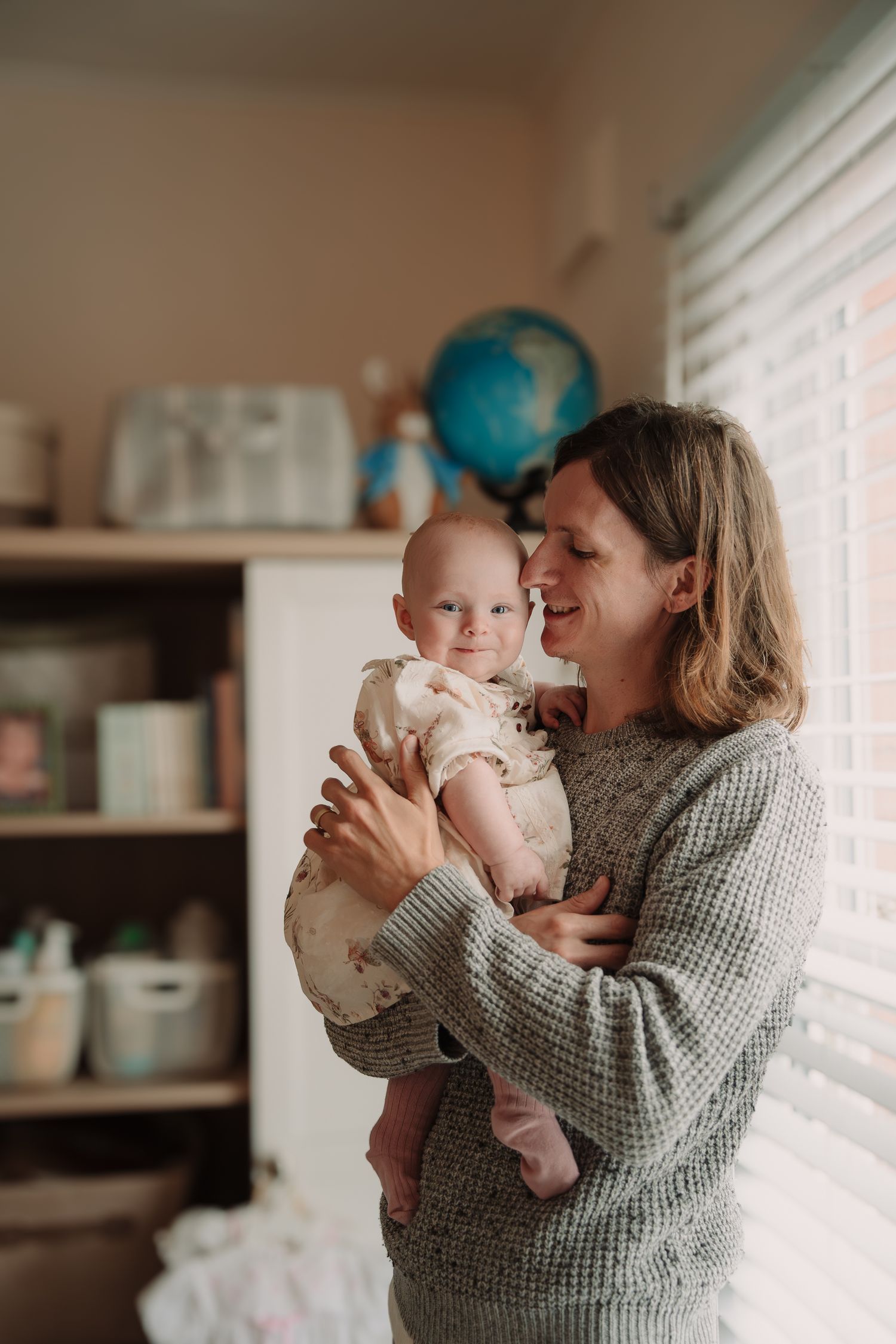 A tender moment between parent and baby is captured in a series of warm-toned photos by a window.
