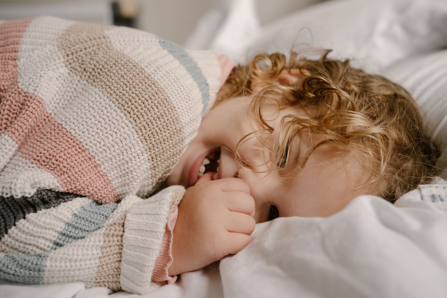 A series of connected images showing a sleeping child with curly hair resting peacefully on white bedding.