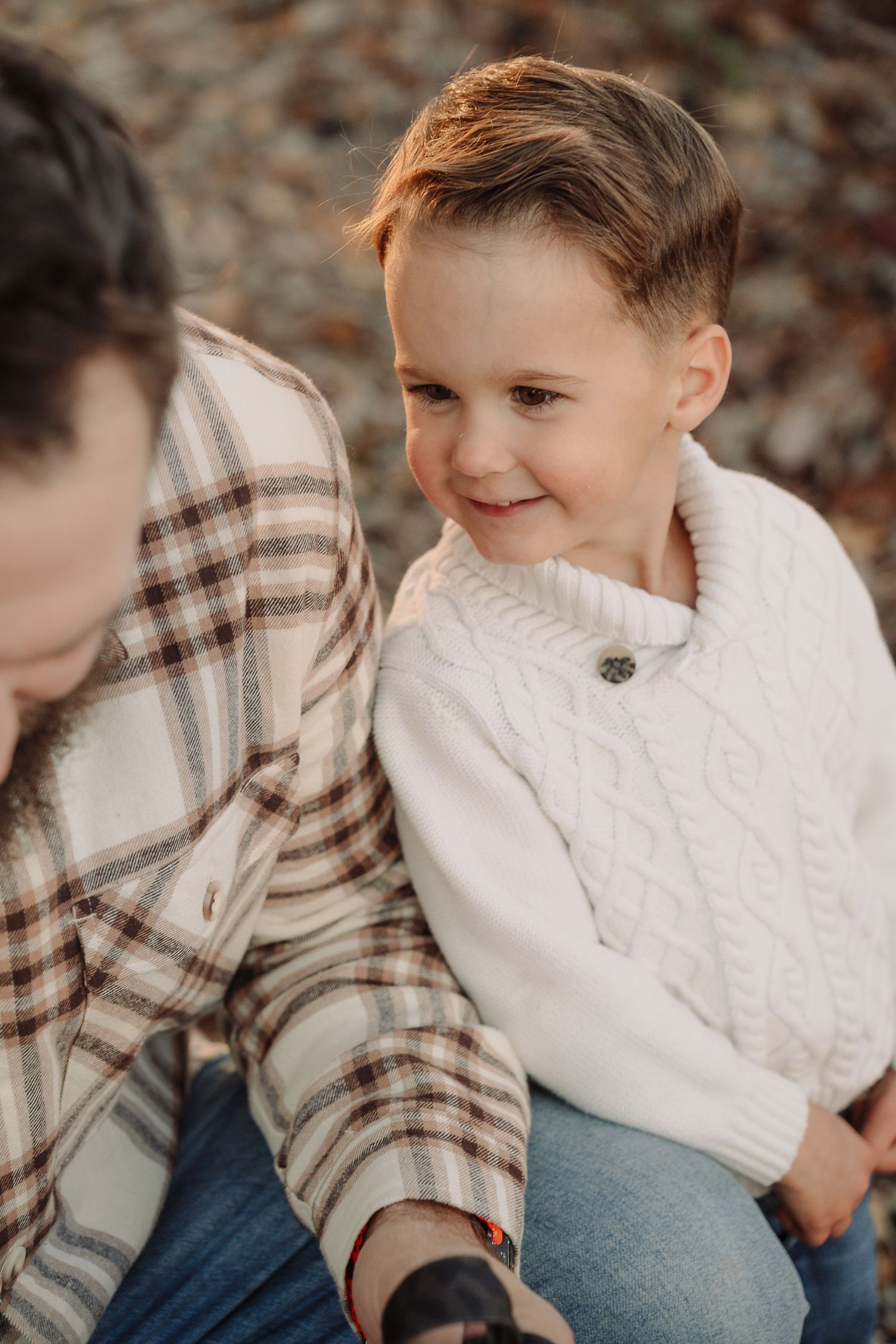 Child in white sweater smiling during autumn family photoshoot.