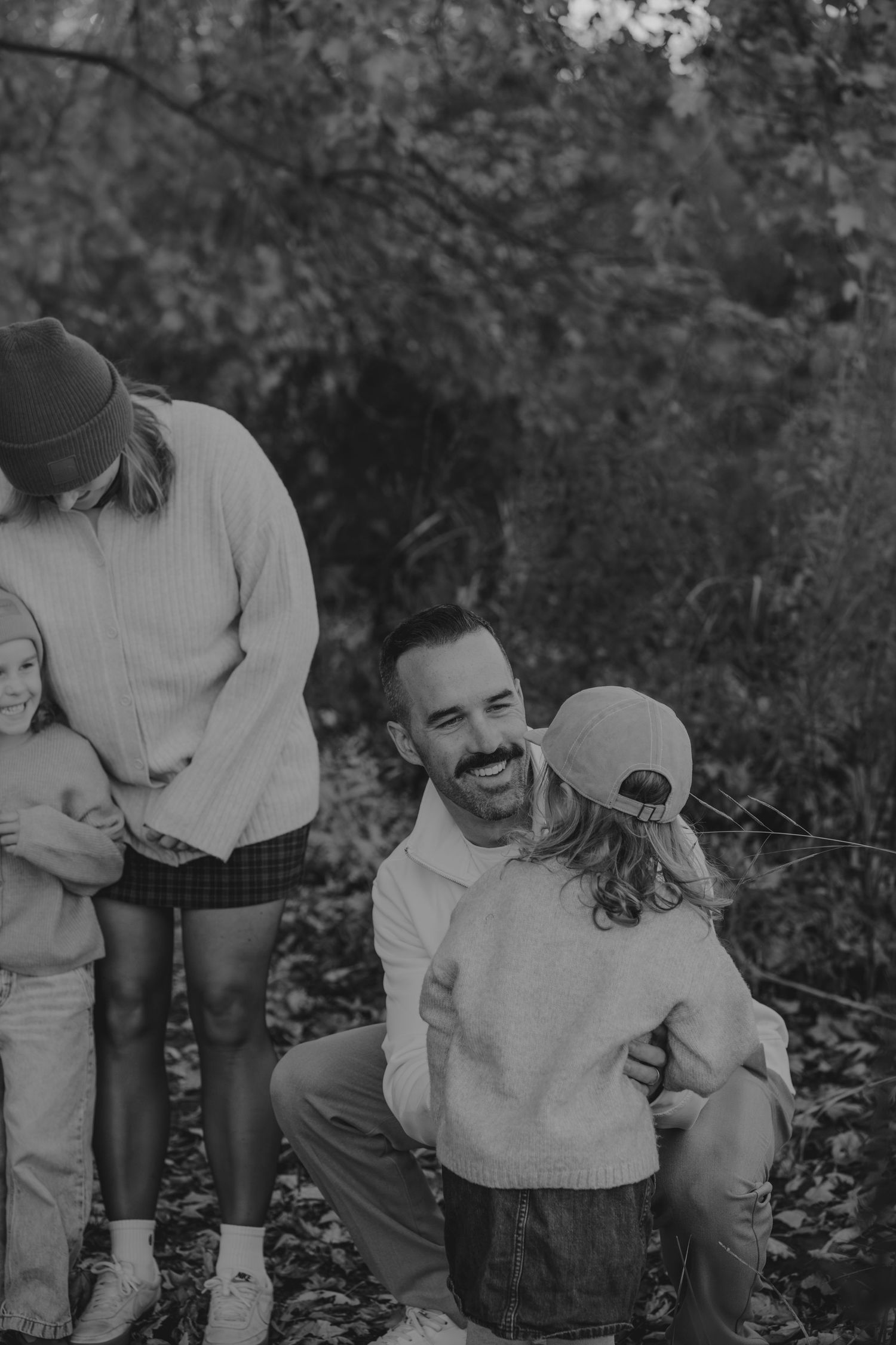 Black and white outdoor sequence capturing playful family moments in a natural setting.