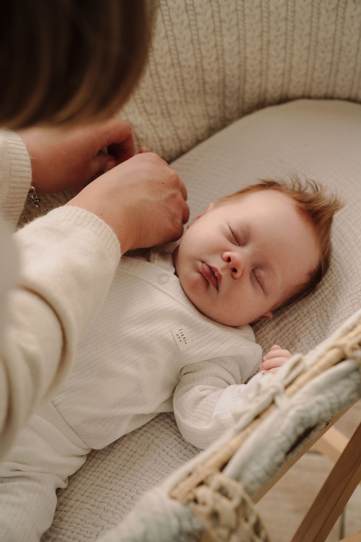 Close-up shots of a sleeping baby in a white sweater on a textured knit blanket.