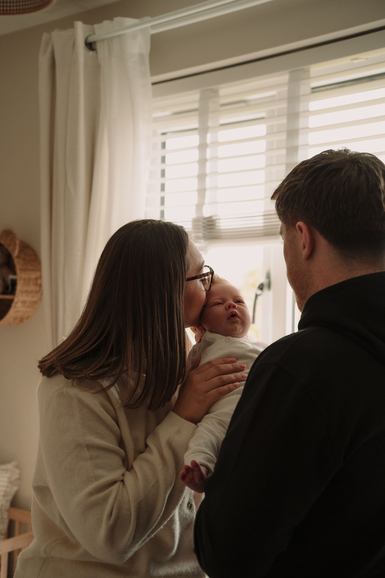 Intimate indoor moment between two people near window blinds.