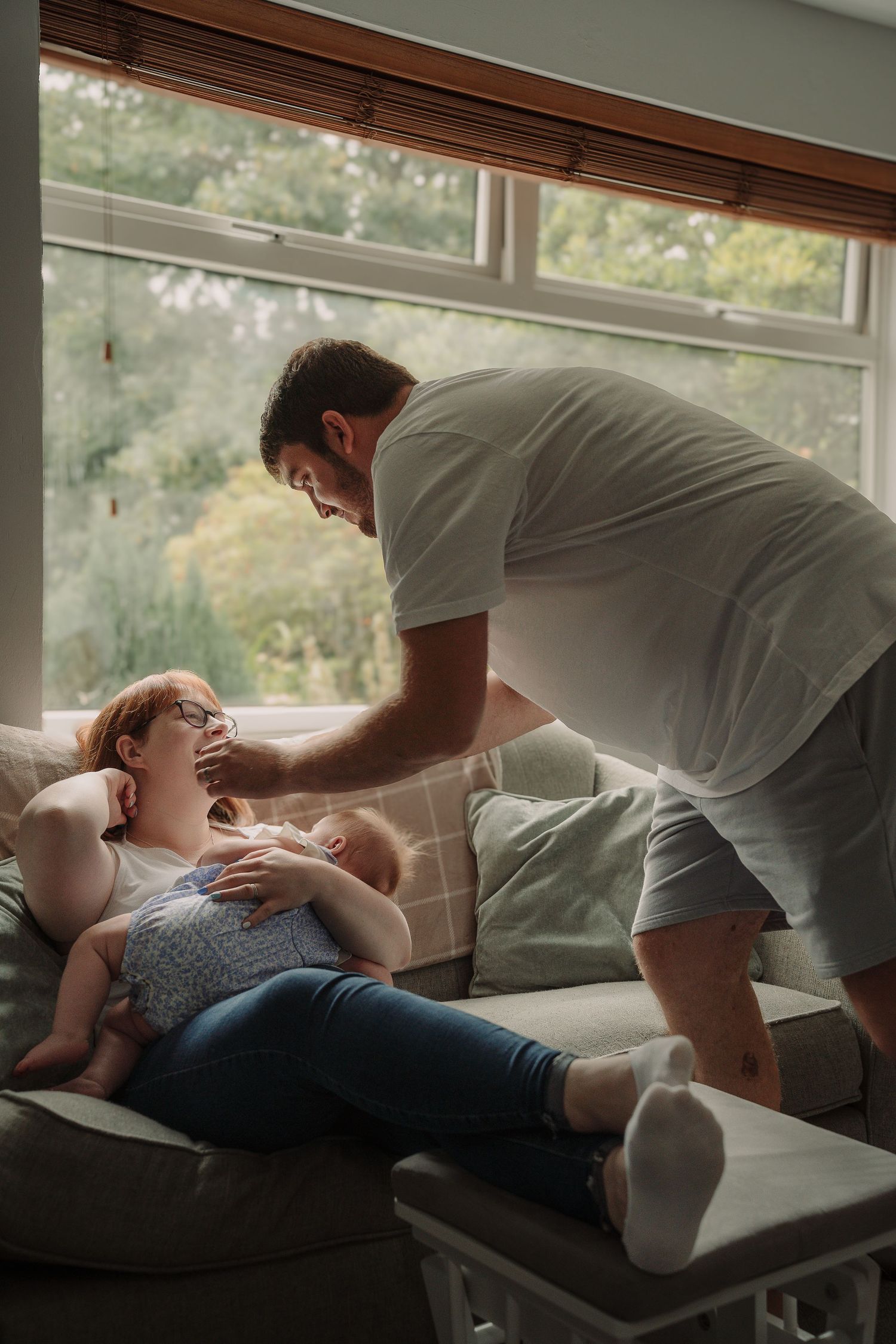 Intimate black and white photo sequence showing tender moments between couple on couch by window.