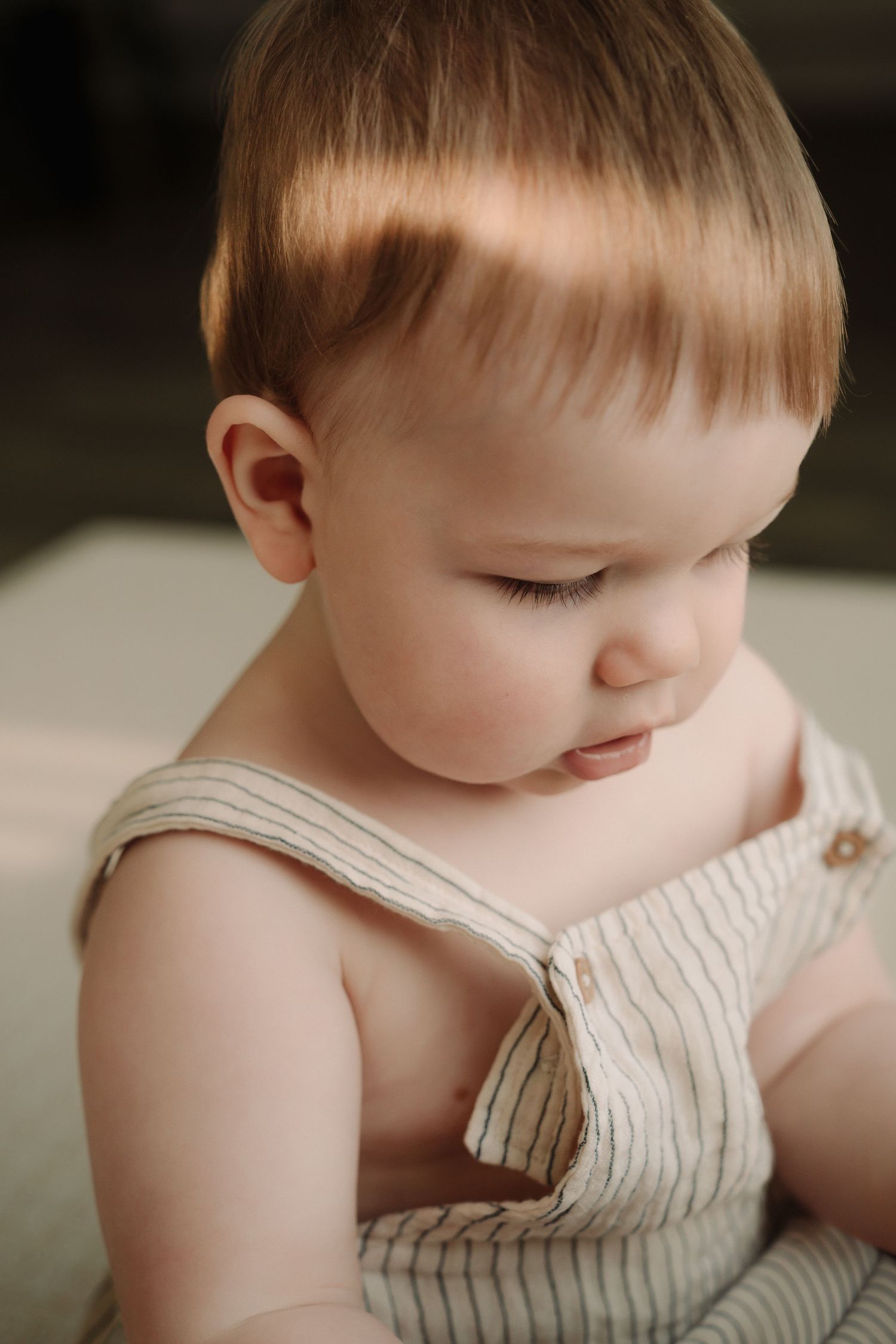 A series of close-up photos showing a baby in a white striped outfit looking down with soft lighting and neutral background.